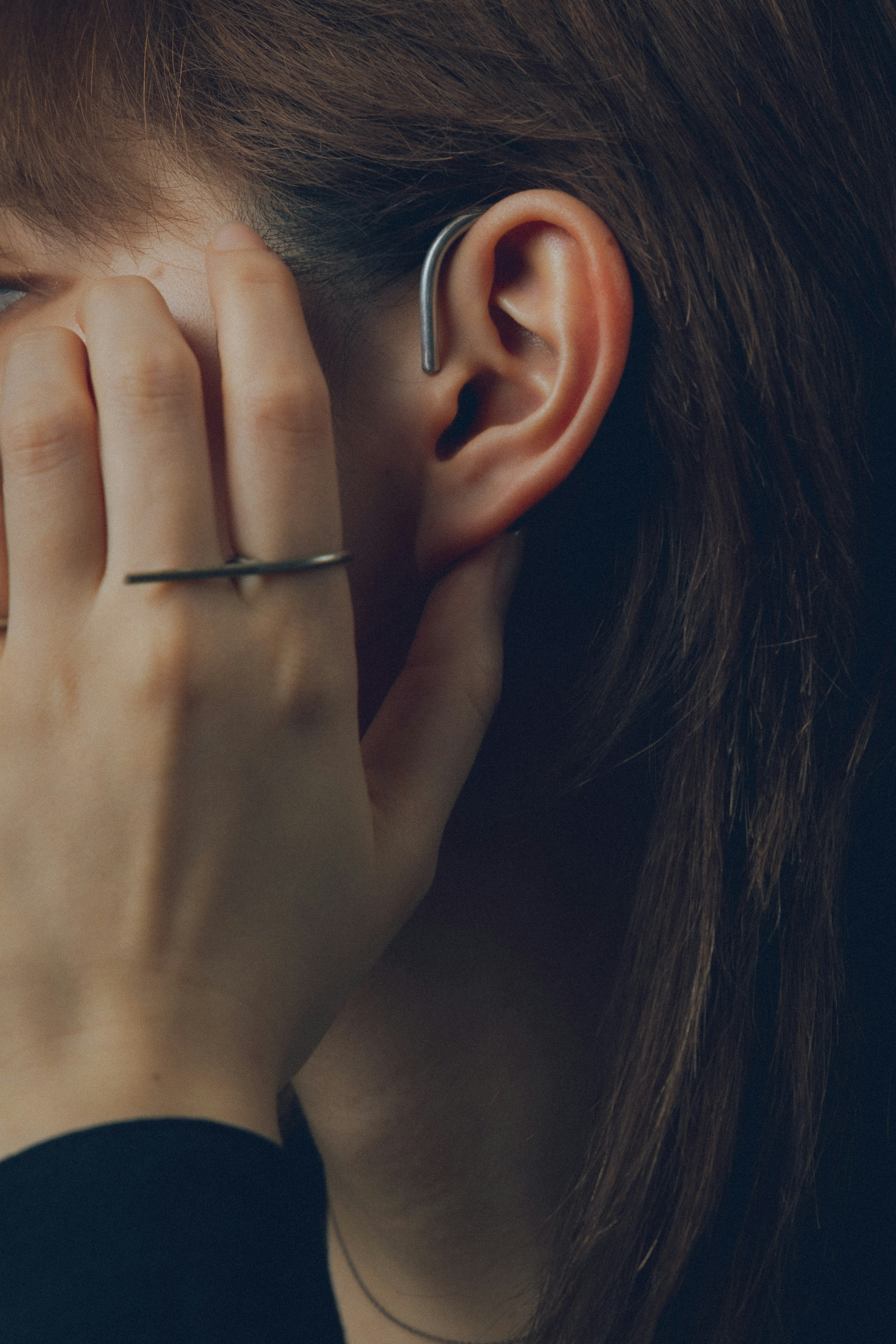 Image of a hand touching the face with an earbud visible in the ear