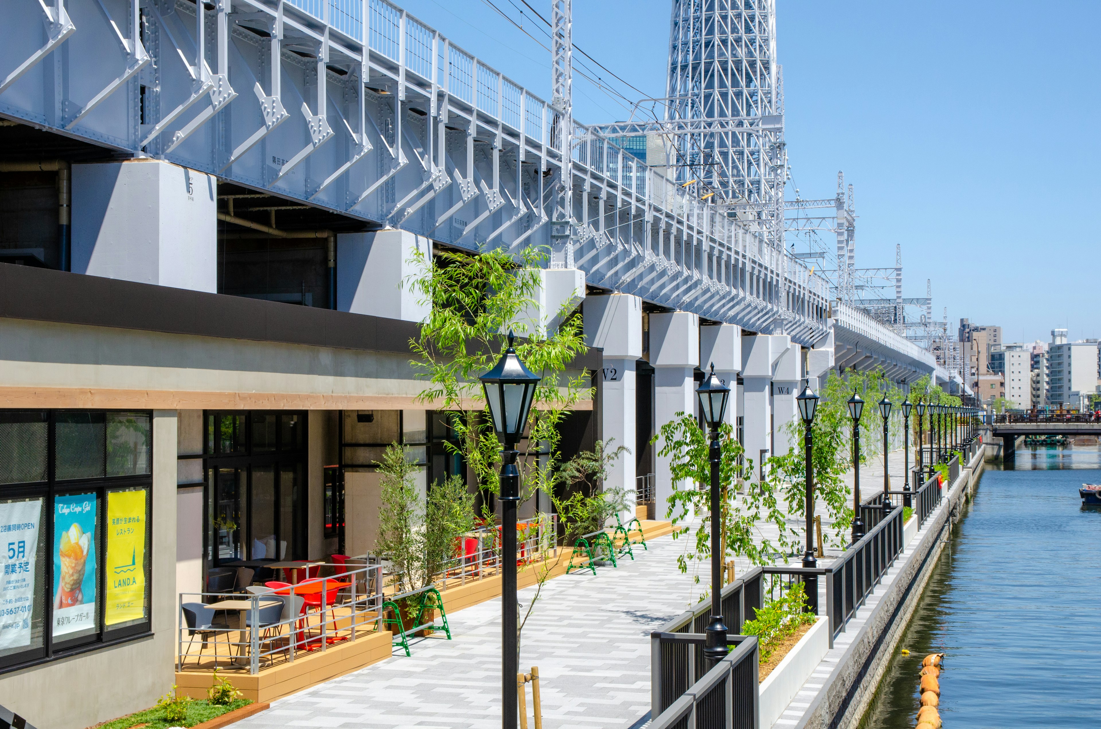 川沿いの整備された歩道とカフェのある景観