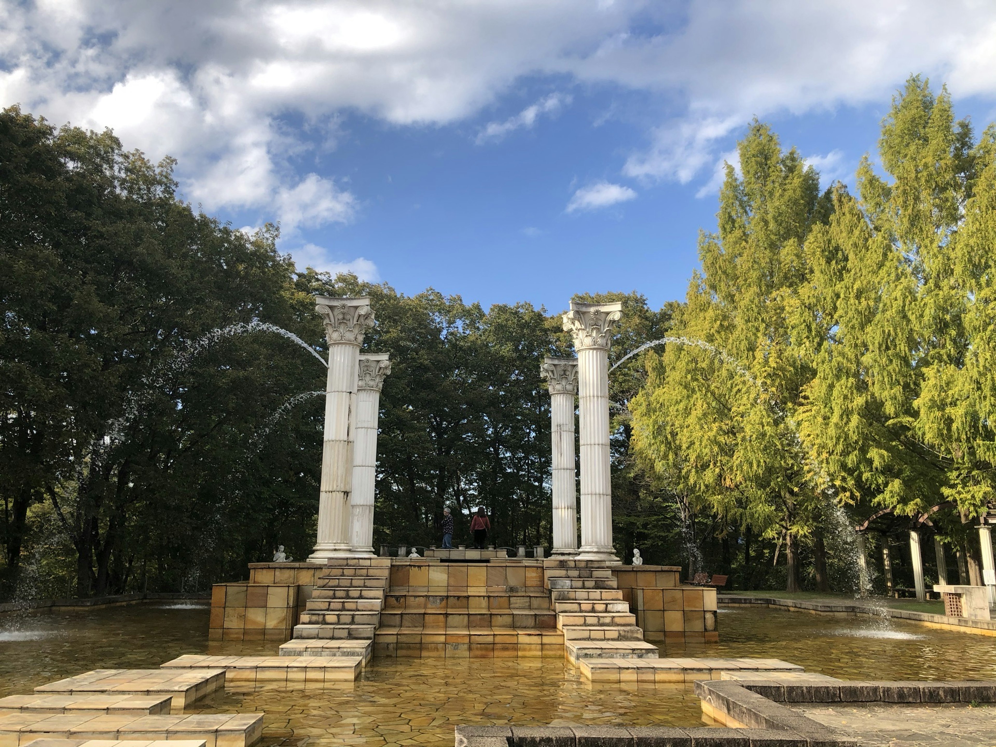 Landscape featuring a fountain and classical columns in a park