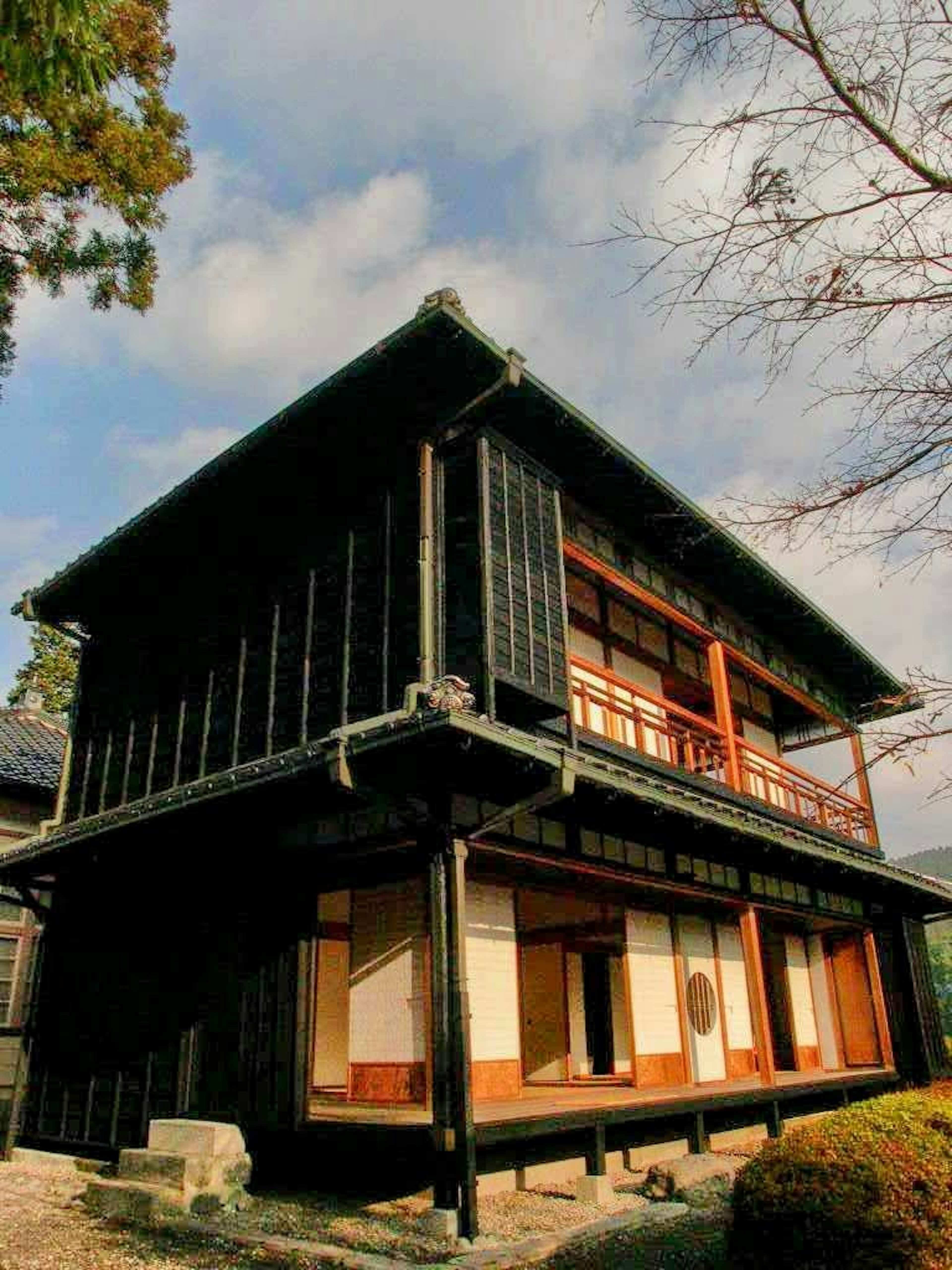 Maison japonaise traditionnelle en bois noir entourée de paysages naturels