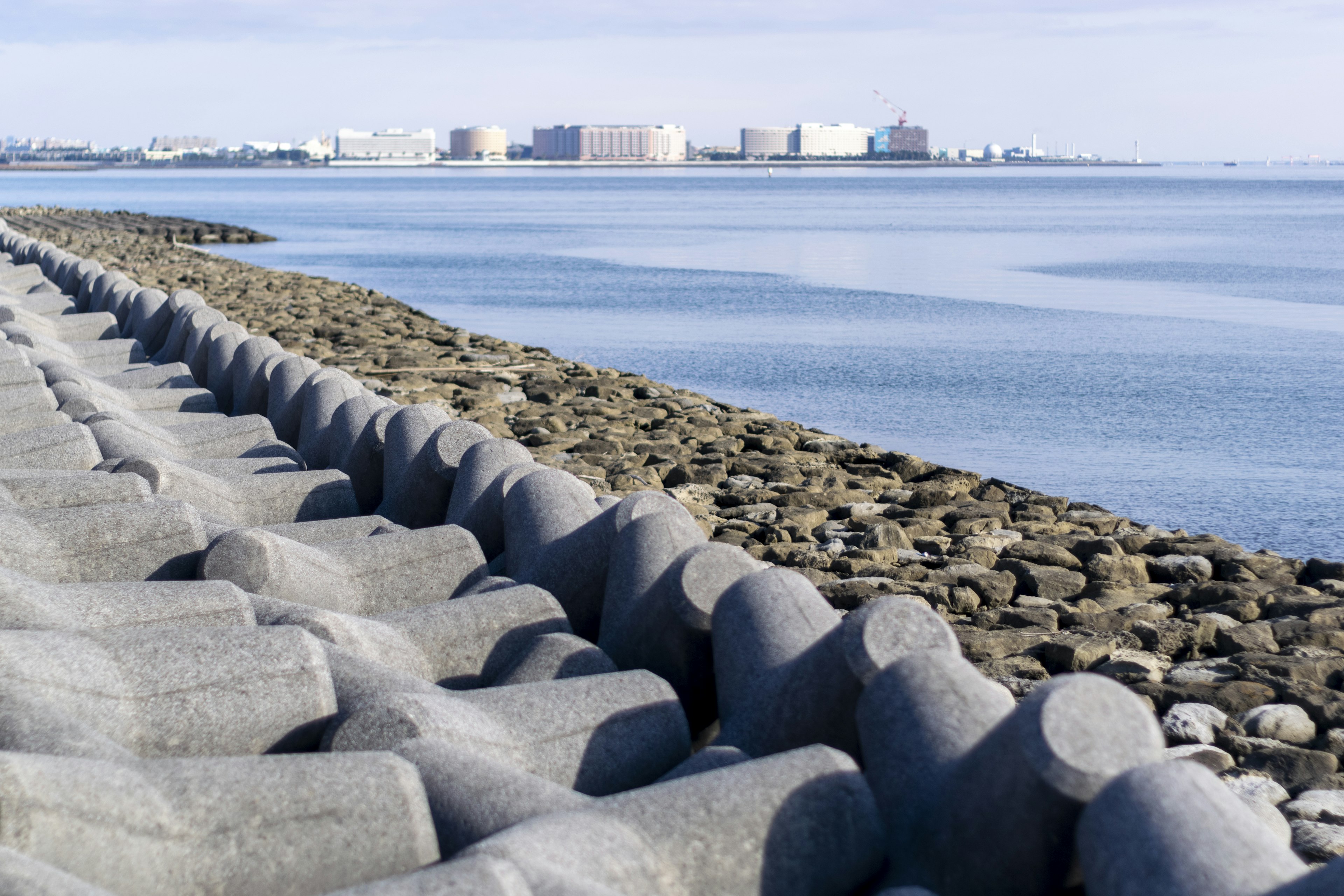 Küstenansicht mit Betonblöcken und ruhiger Wasseroberfläche