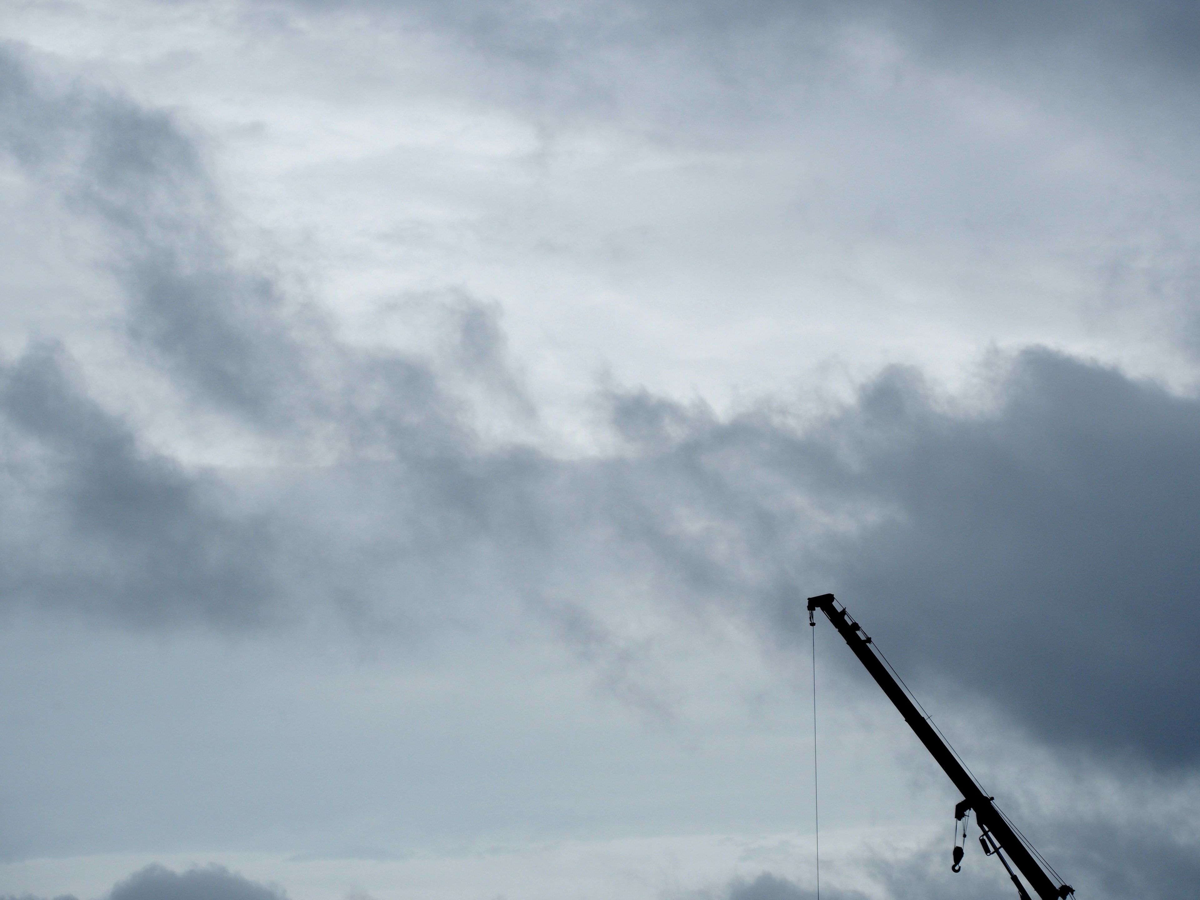 Foto di un cielo grigio con nuvole e la silhouette di una gru