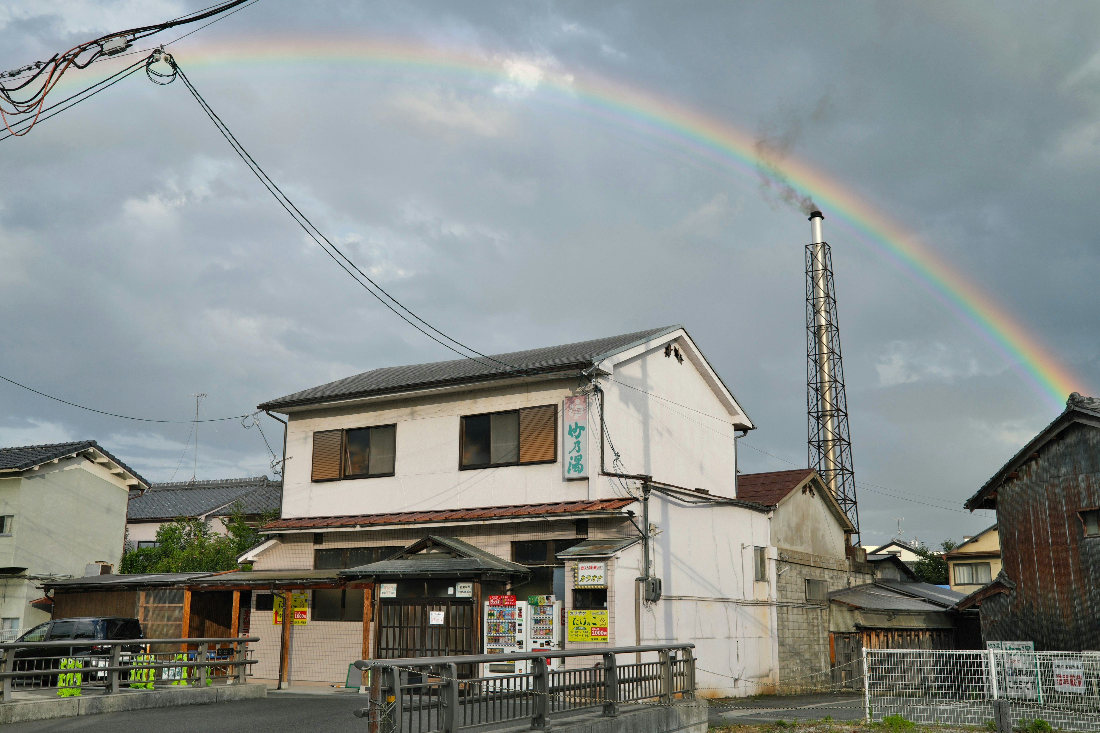 虹の下にある白い家と周囲の建物