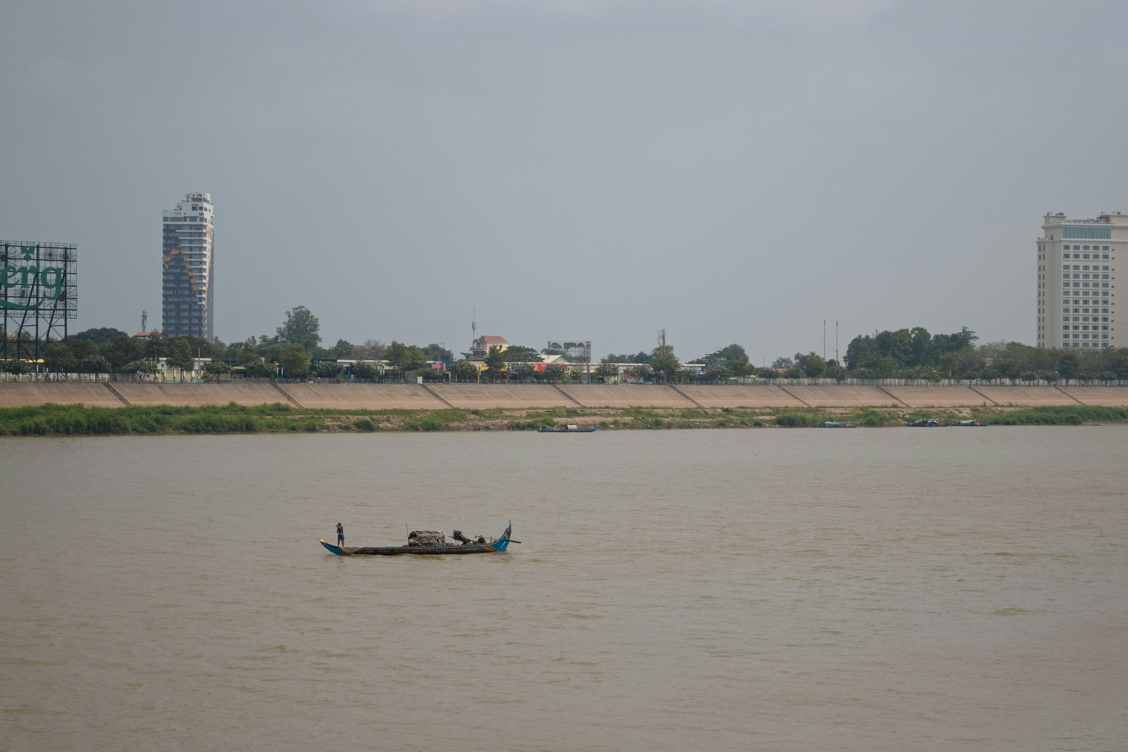 Un petit bateau sur une rivière avec un skyline urbain