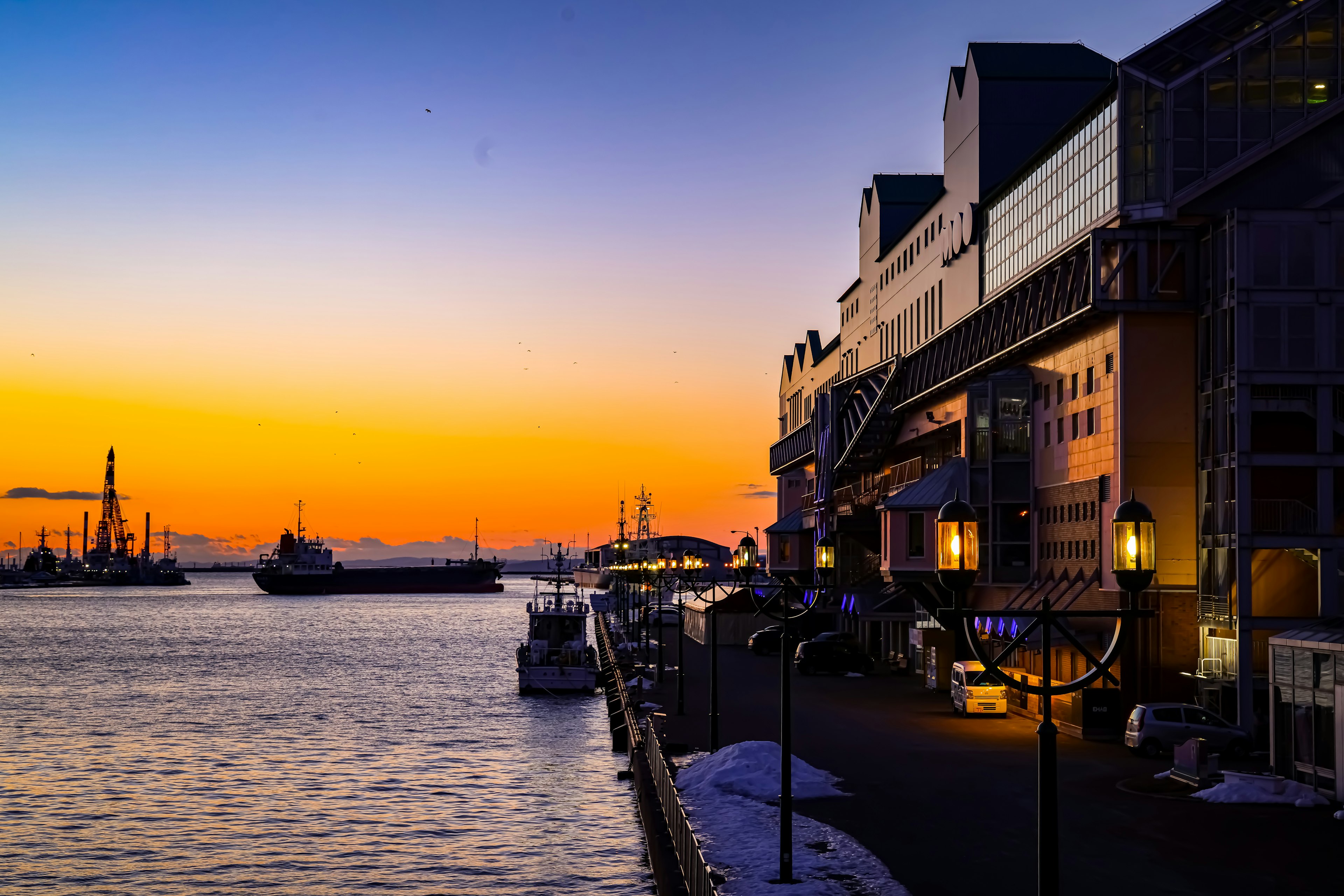 Harbor view at sunset with silhouettes of buildings