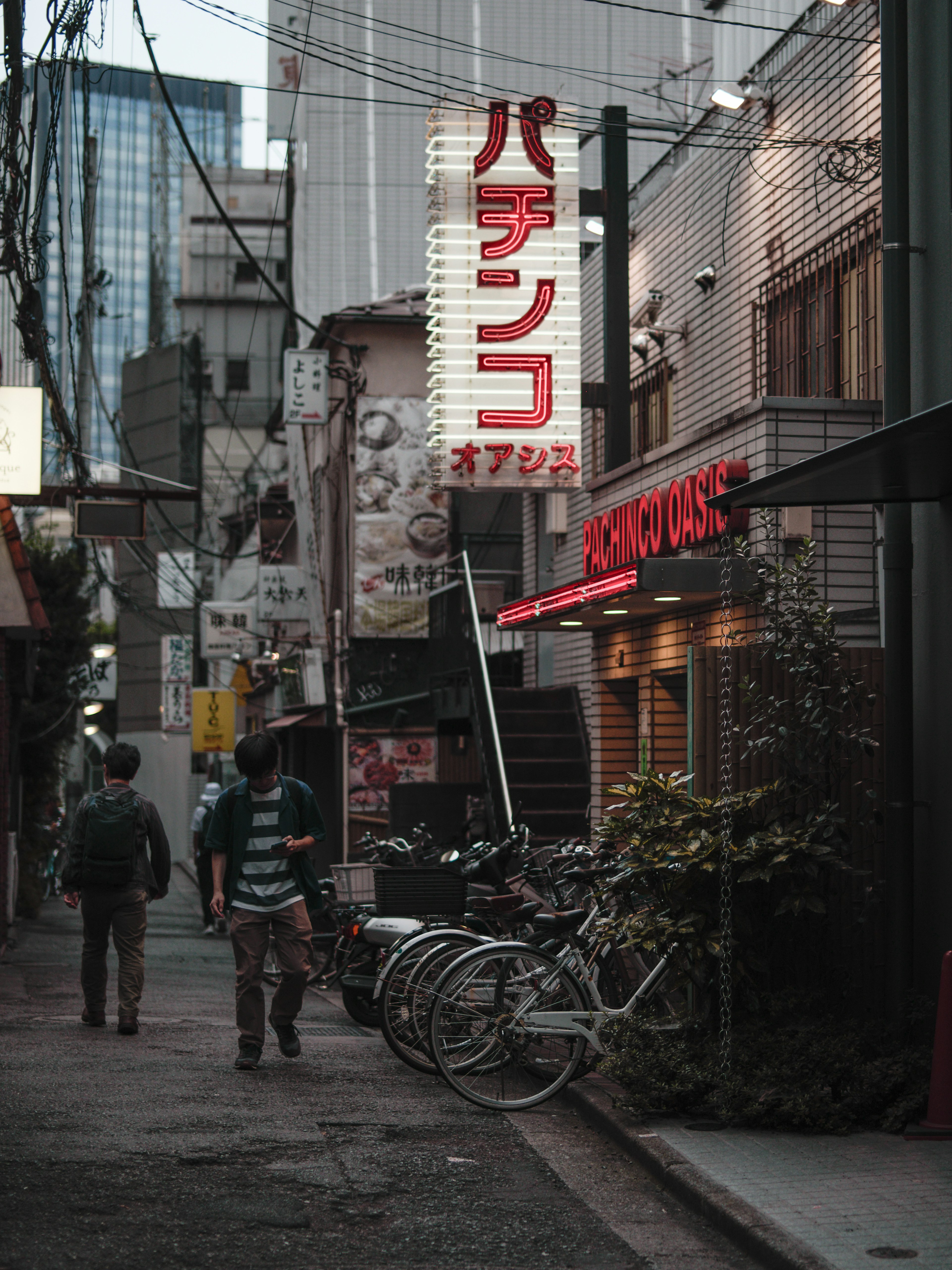 Schmale Gasse mit Geschäften und Fahrrädern, die ein auffälliges Pachinko-Schild zeigen