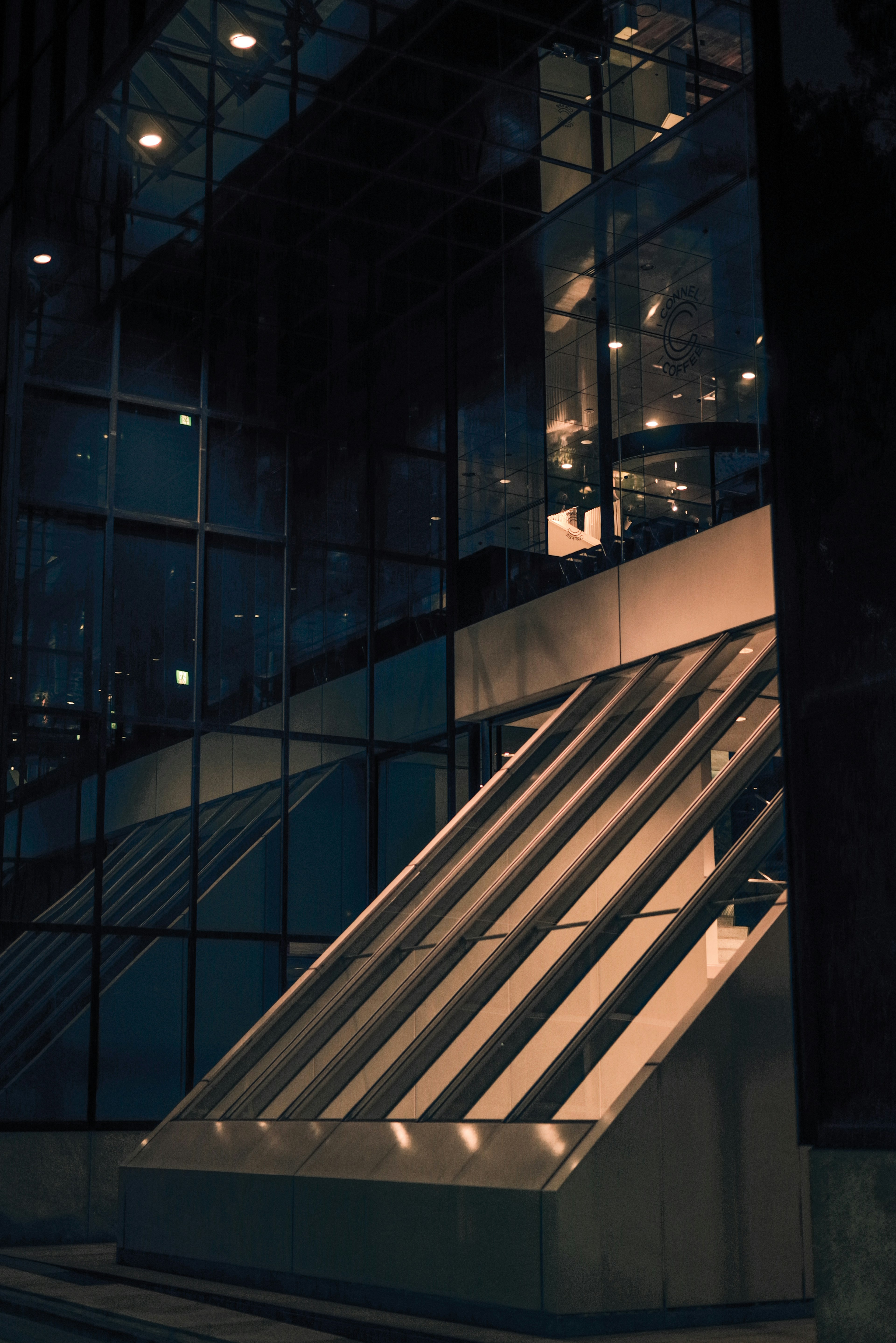 Extérieur d'un bâtiment moderne la nuit avec des murs en verre et des escaliers inclinés