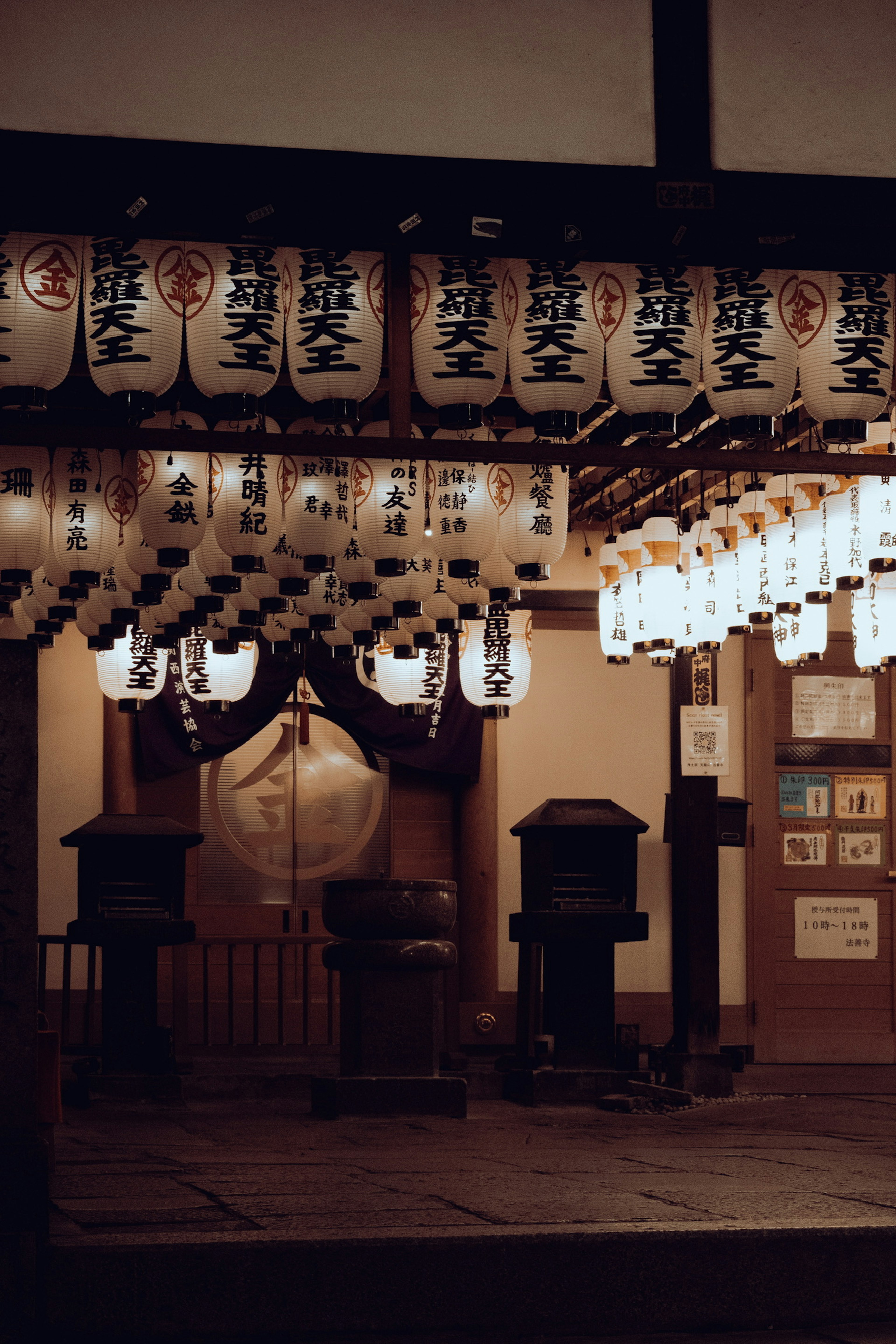 Eingang eines traditionellen japanischen Schreins, geschmückt mit Laternen und Lichtern bei Nacht