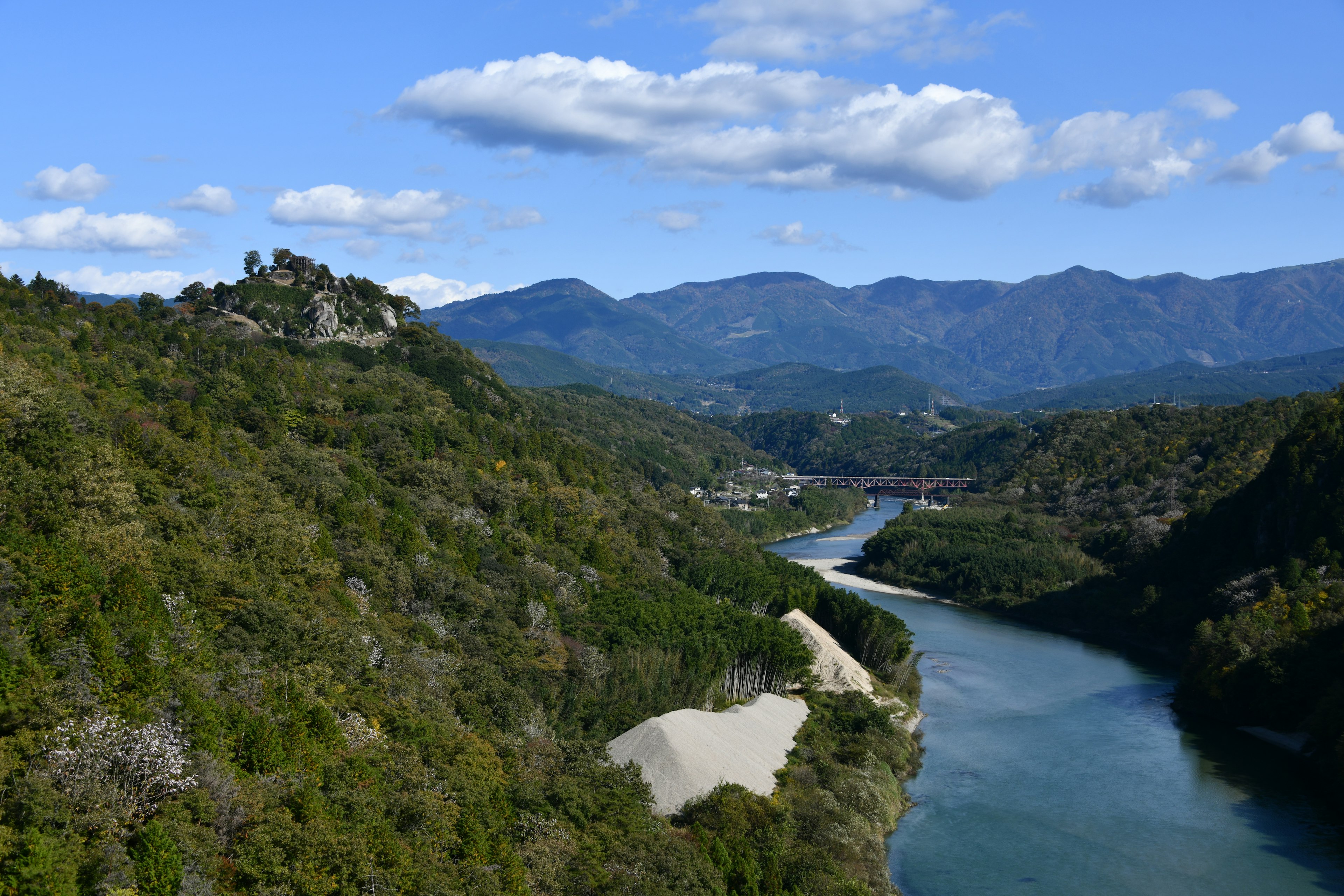 Grüne Berge und ein gewundener Fluss unter einem blauen Himmel mit weißen Wolken