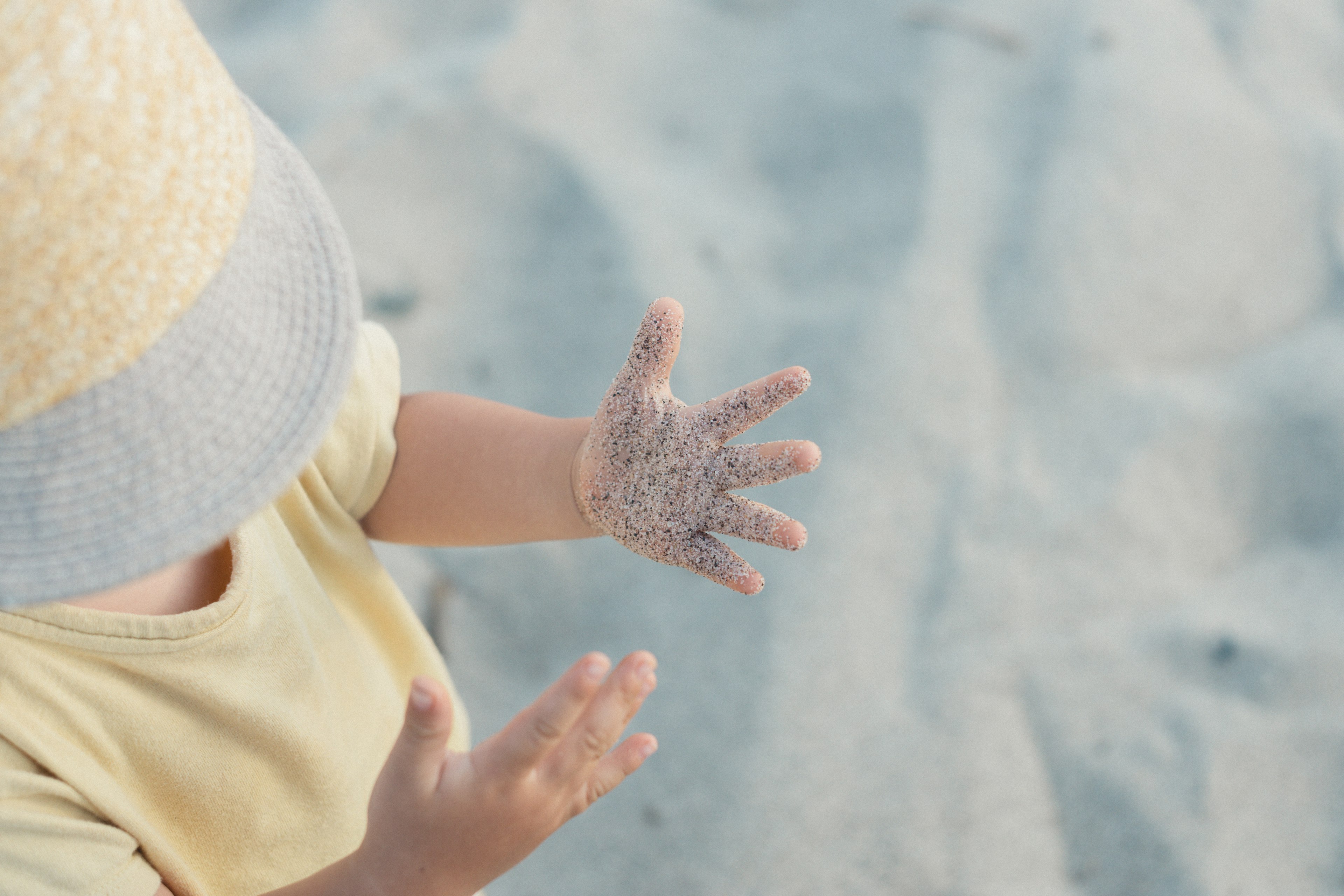 Child's hand covered in sand on the beach