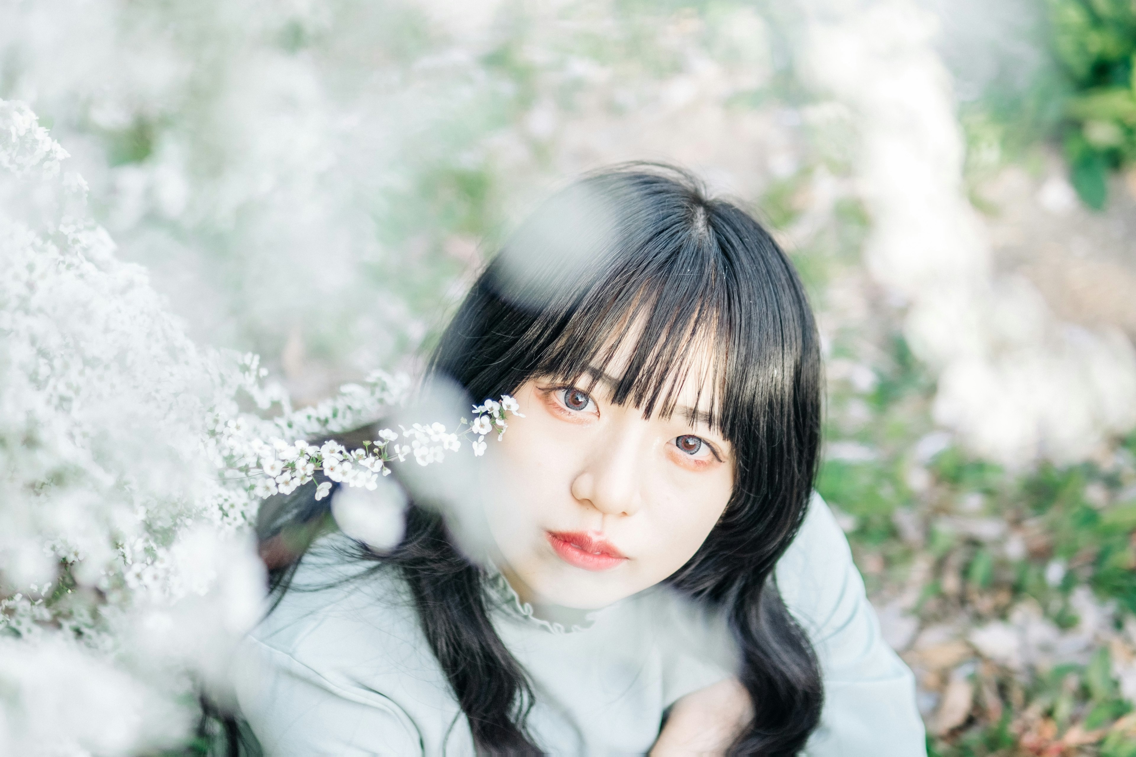 Retrato de una mujer sentada cerca de flores blancas con luz suave y fondo natural