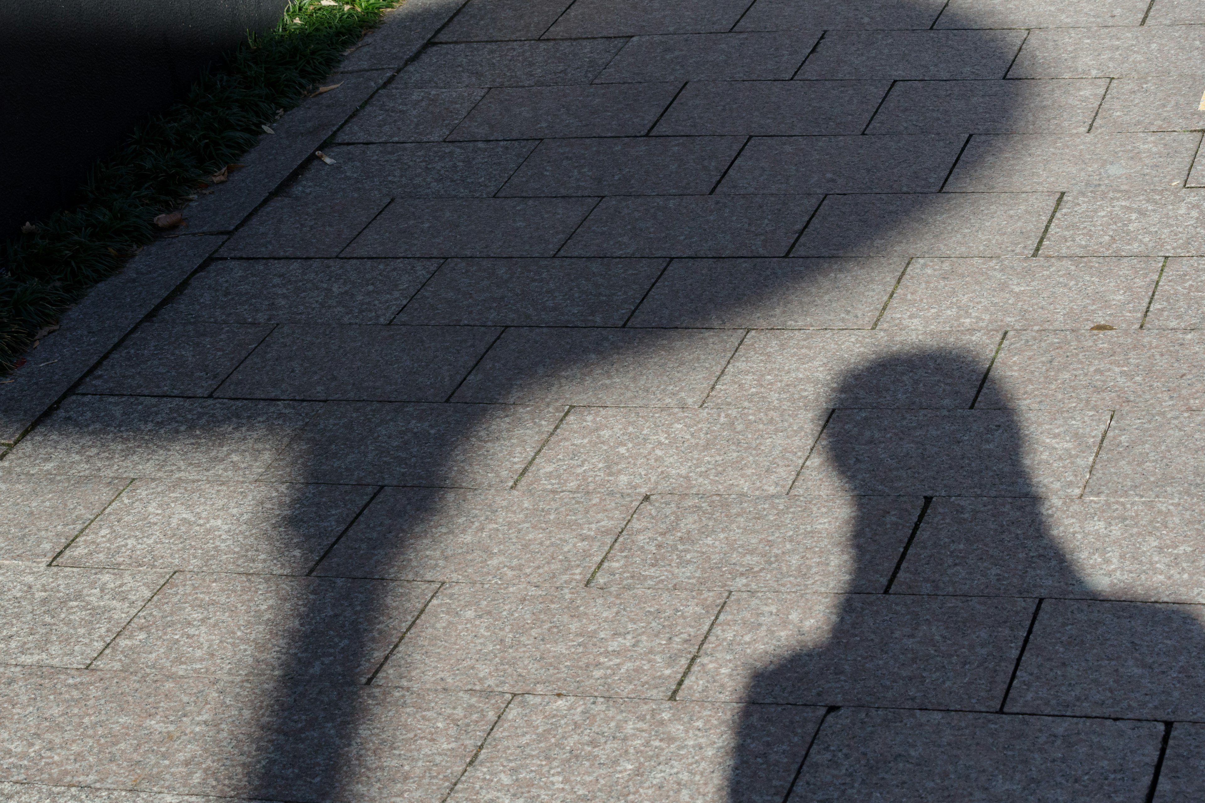 Ombre d'une personne et d'un panneau de rue sur le pavé