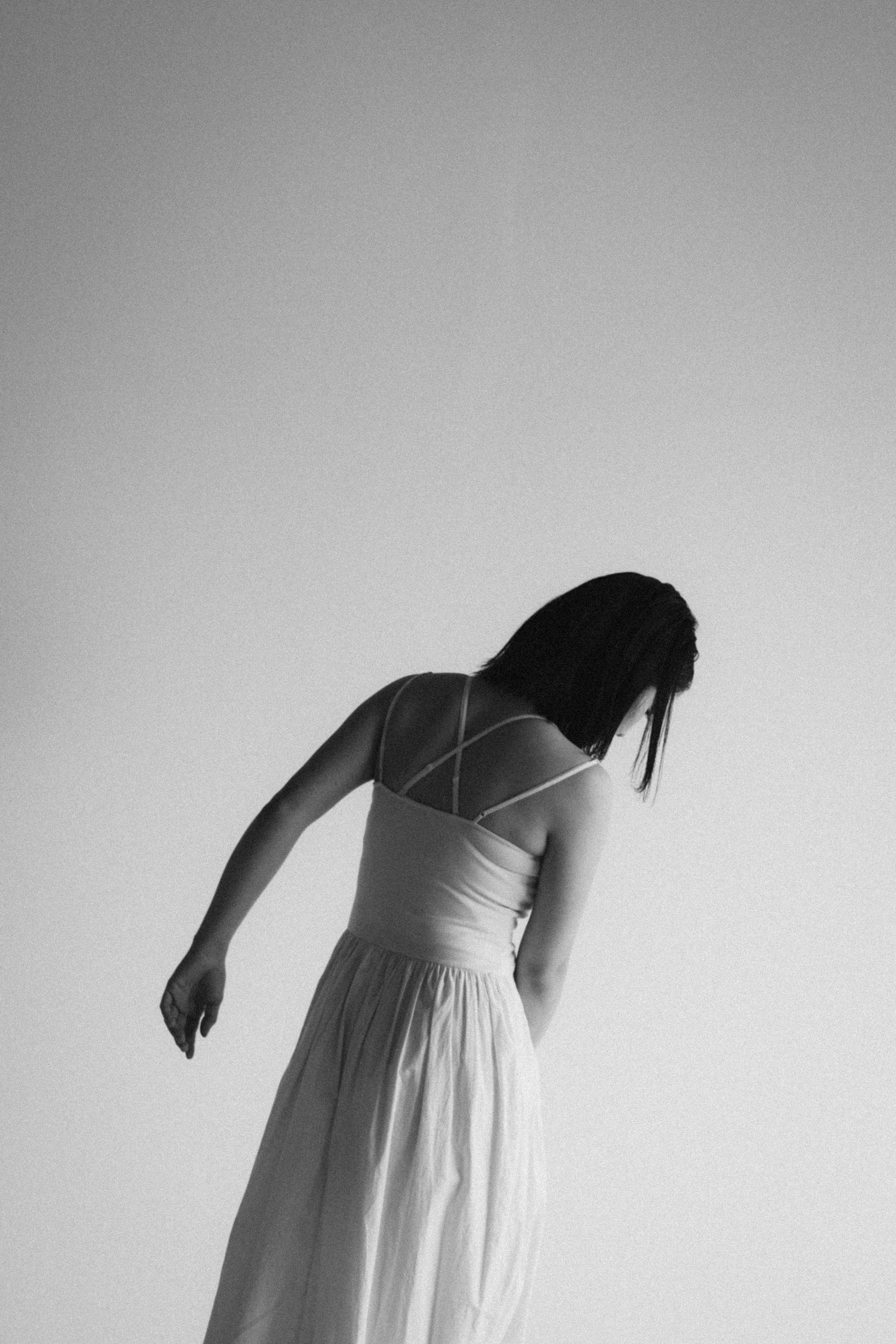 Une femme en robe blanche de dos dans une image en noir et blanc