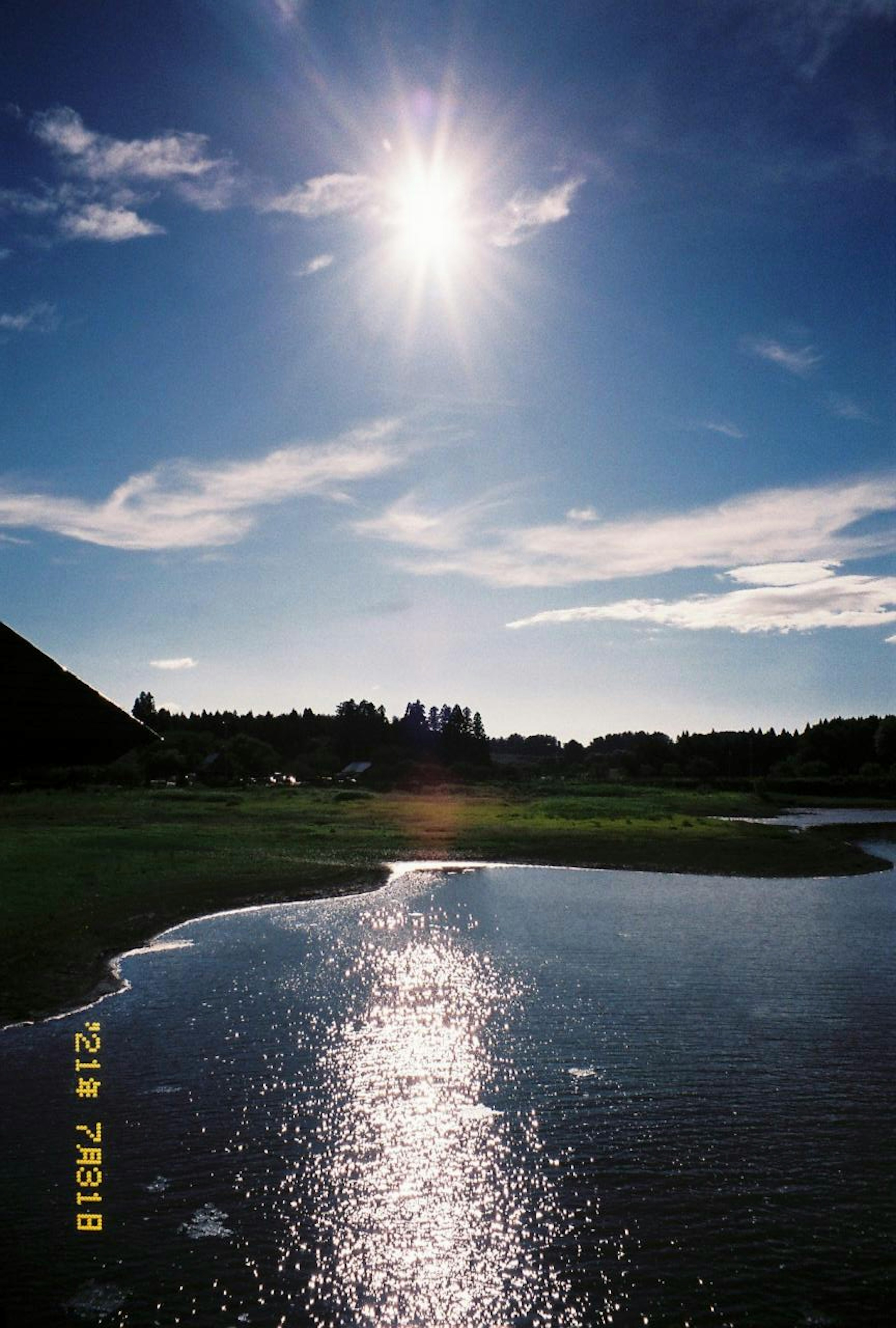 青空に輝く太陽と水面の反射が美しい風景