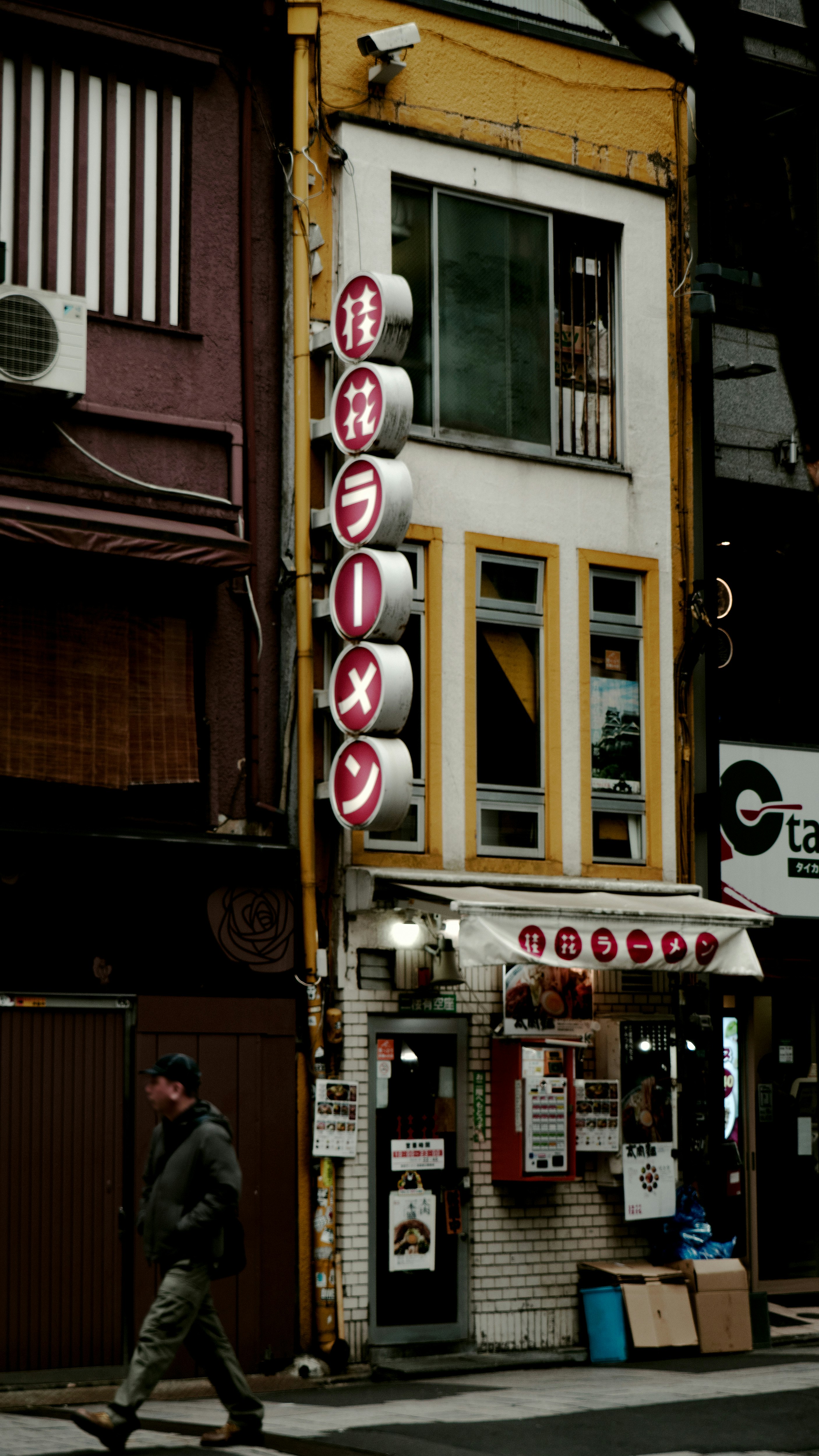 Fassade eines Ramen-Restaurants mit gelben Fenstern und rotem Schild