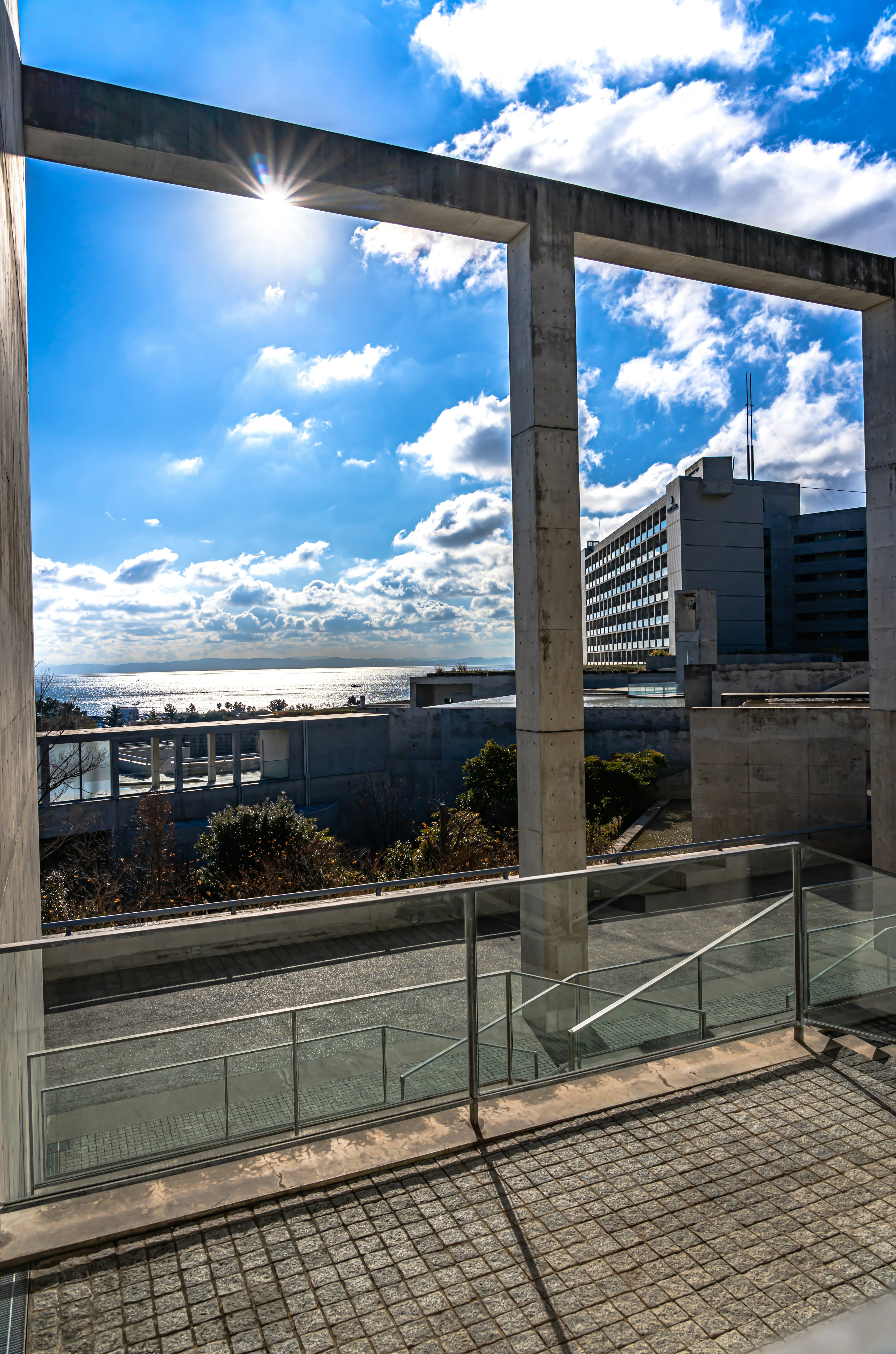 Vue d'un bâtiment moderne et d'un front de mer sous un ciel bleu brillant avec des nuages