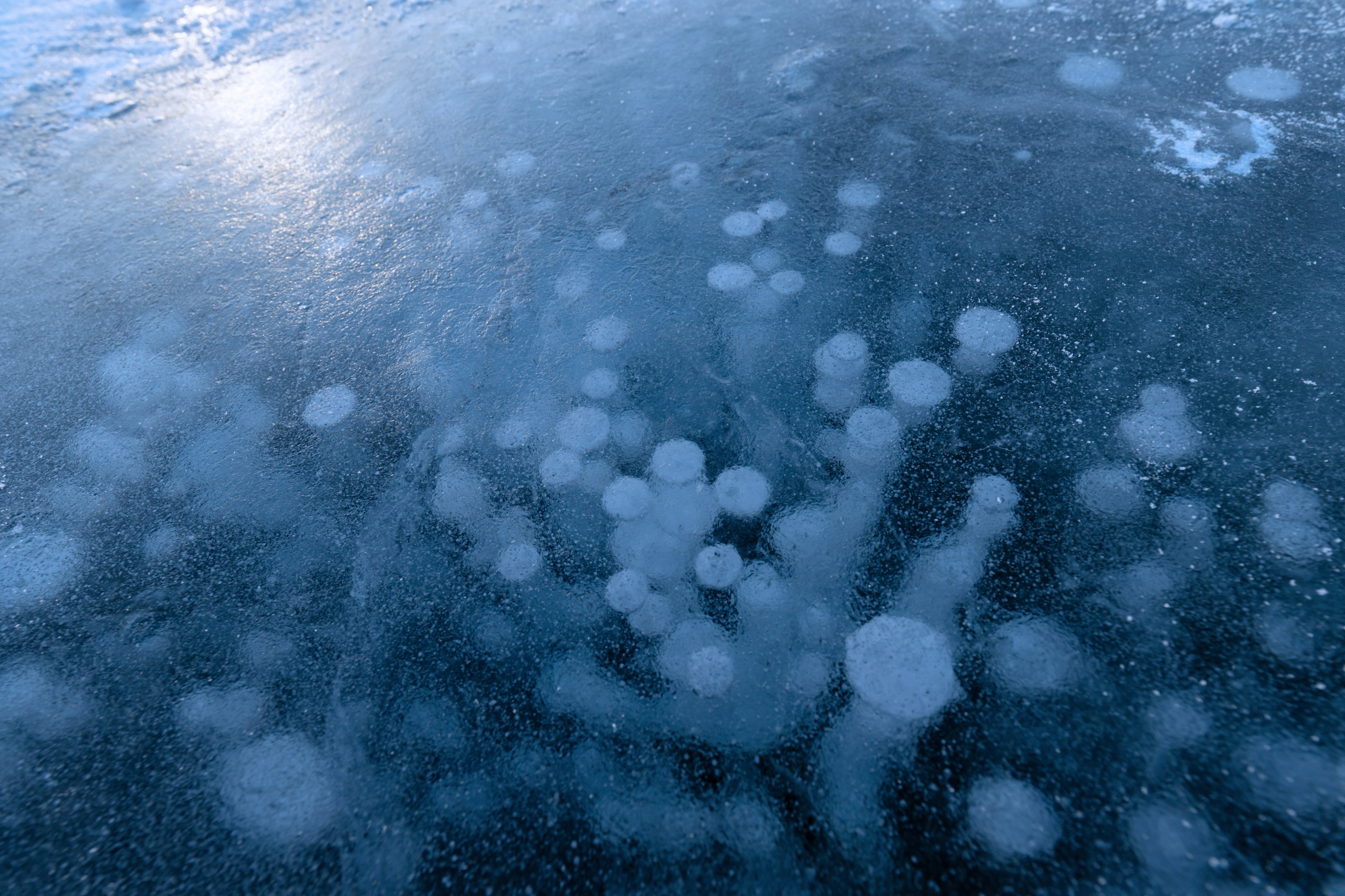 Burbujas atrapadas bajo el hielo, superficie de hielo azul, belleza natural