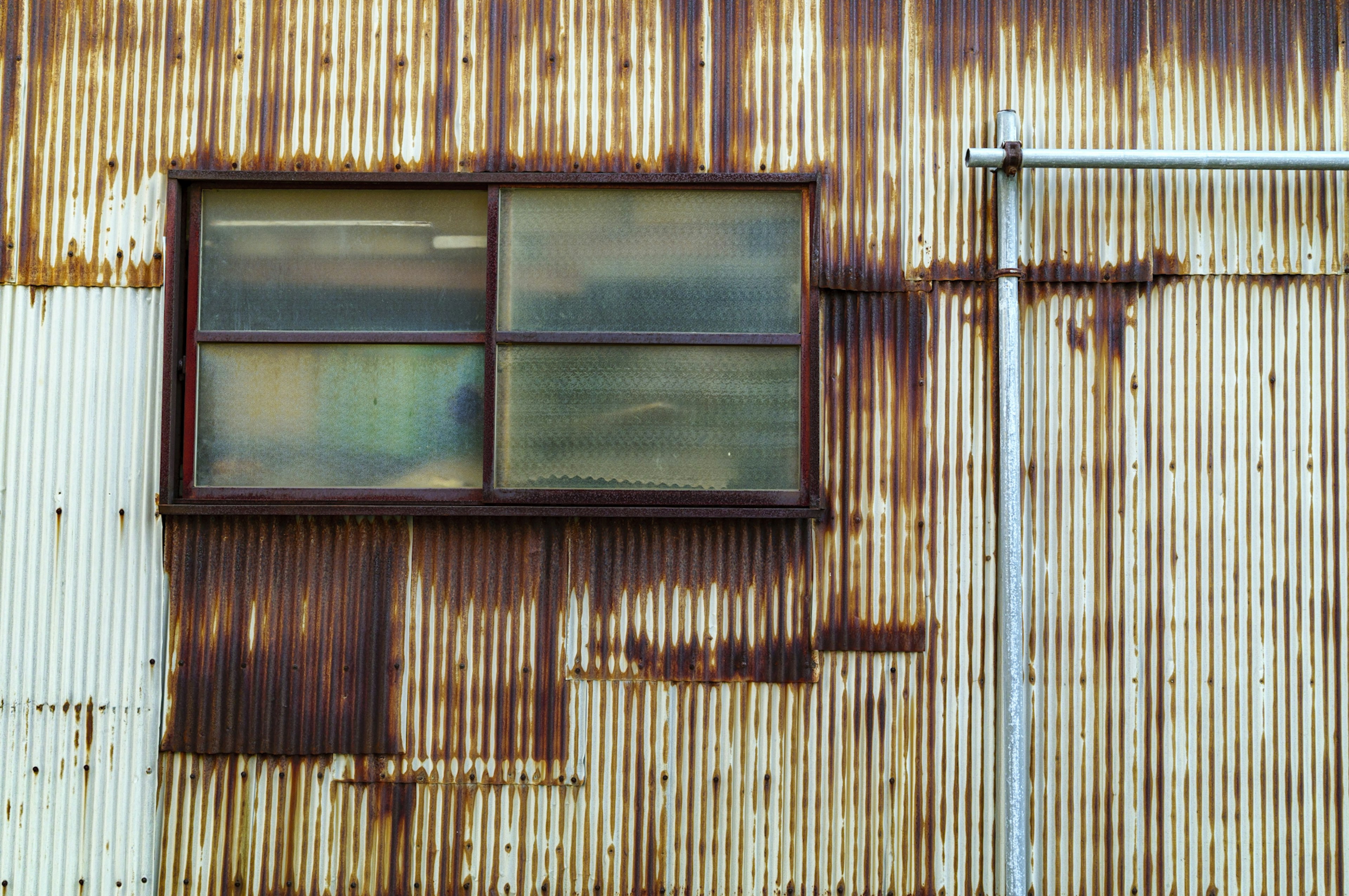 Exterior de una fábrica con una ventana en una pared de metal oxidado