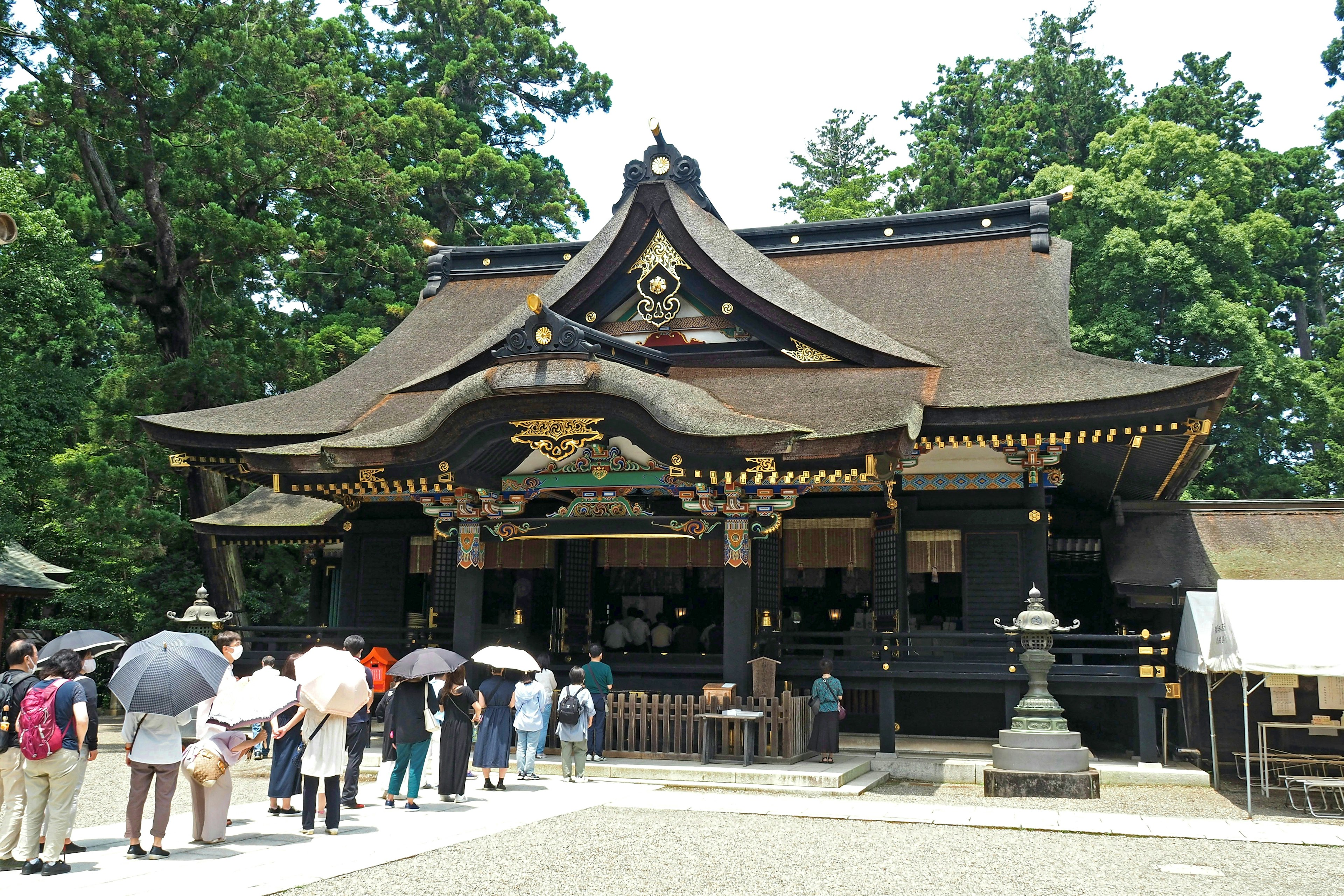 人们在神社前排队，手里拿着雨伞