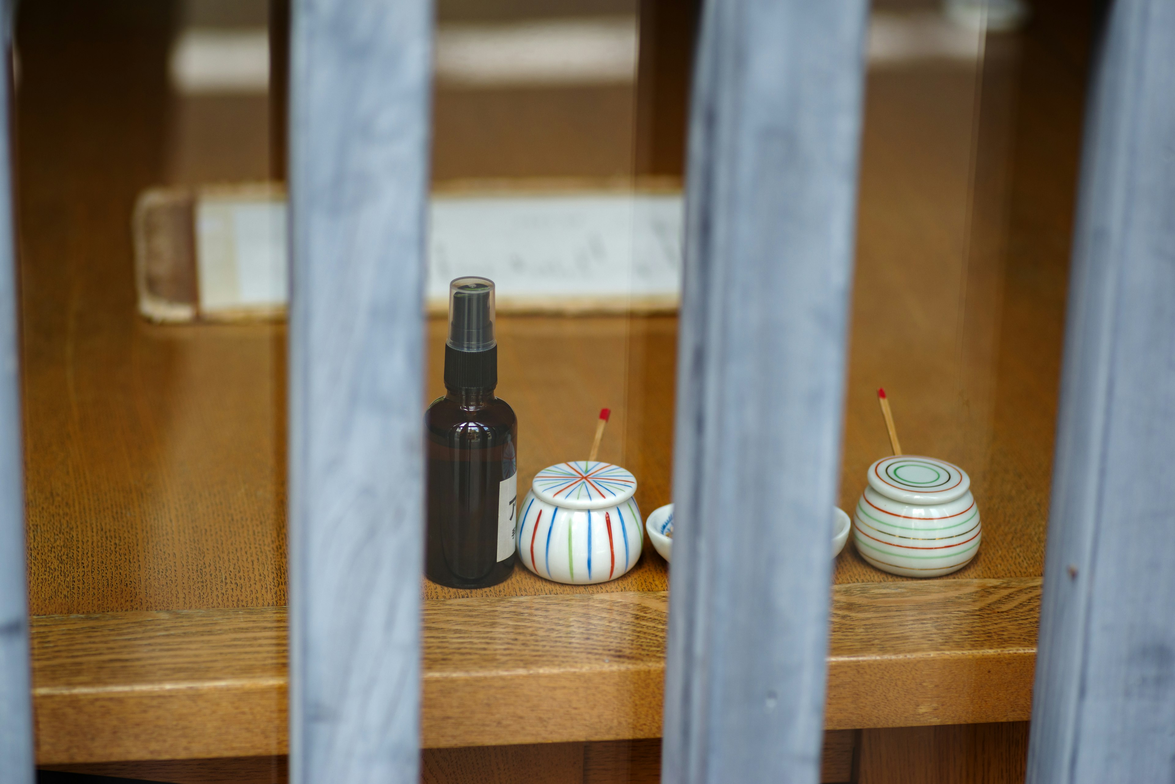 Petits contenants et bouteille en spray disposés sur une étagère en bois