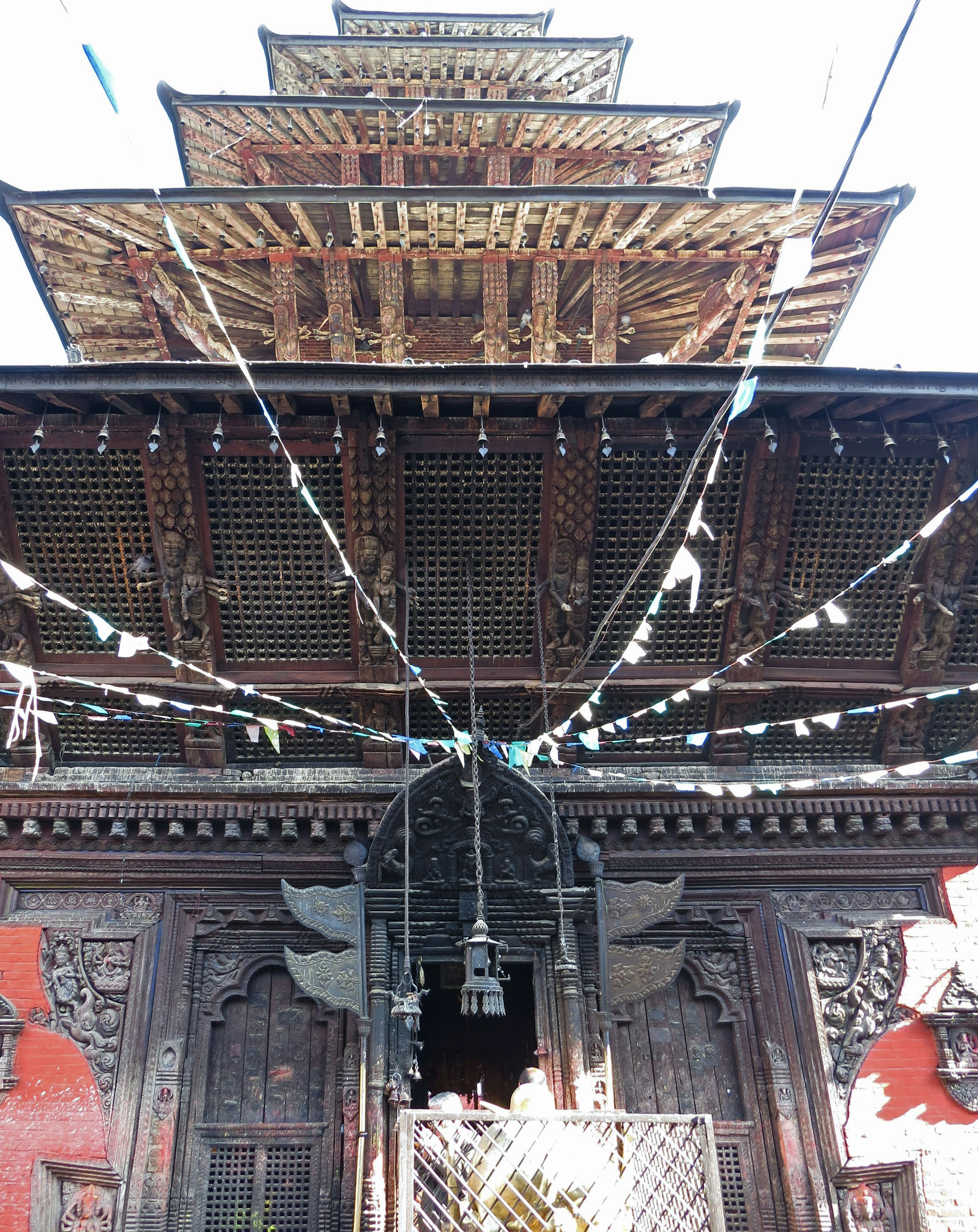 木造の寺院の入り口にある装飾的な彫刻と鐘