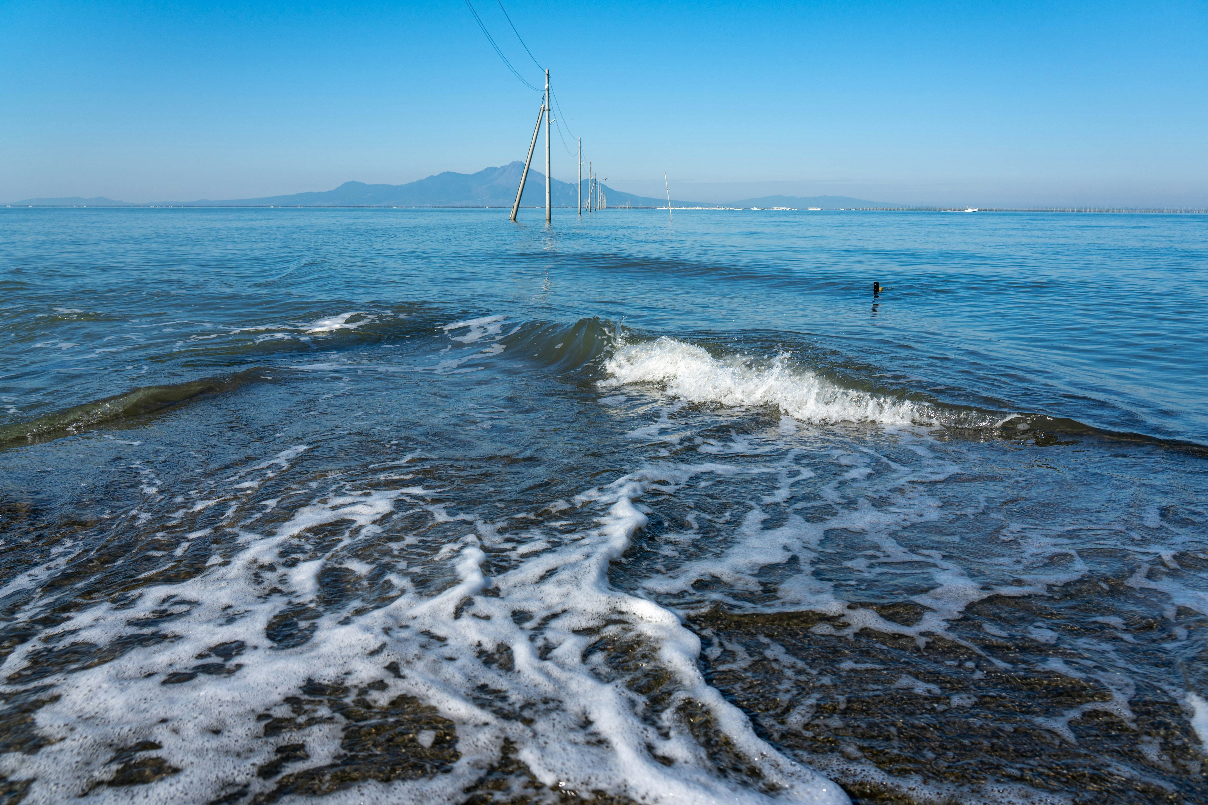 平静的海洋和拍打海岸的波浪远处的山脉