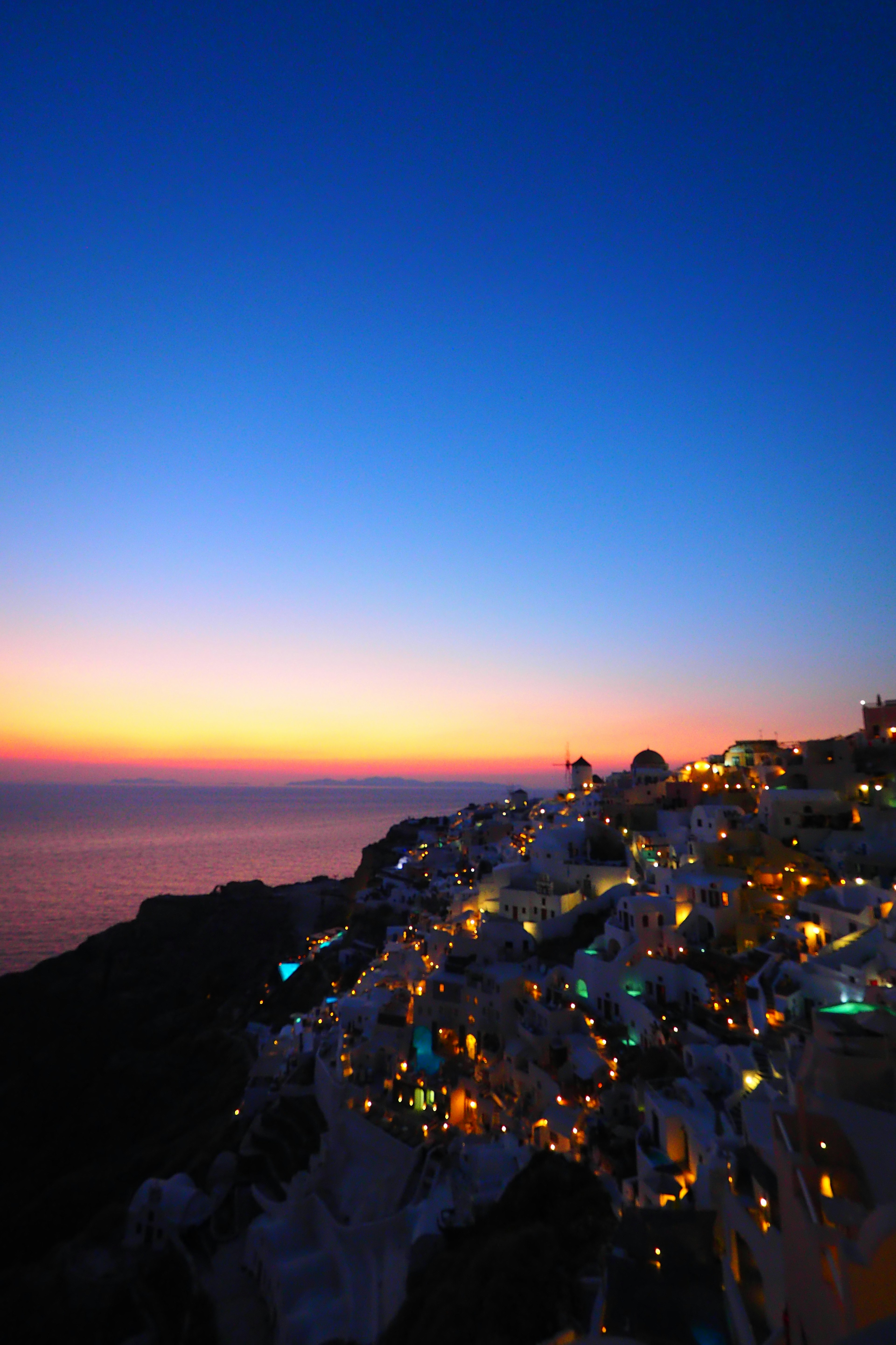 Beeindruckender Sonnenuntergang über Santorin mit beleuchteten Gebäuden