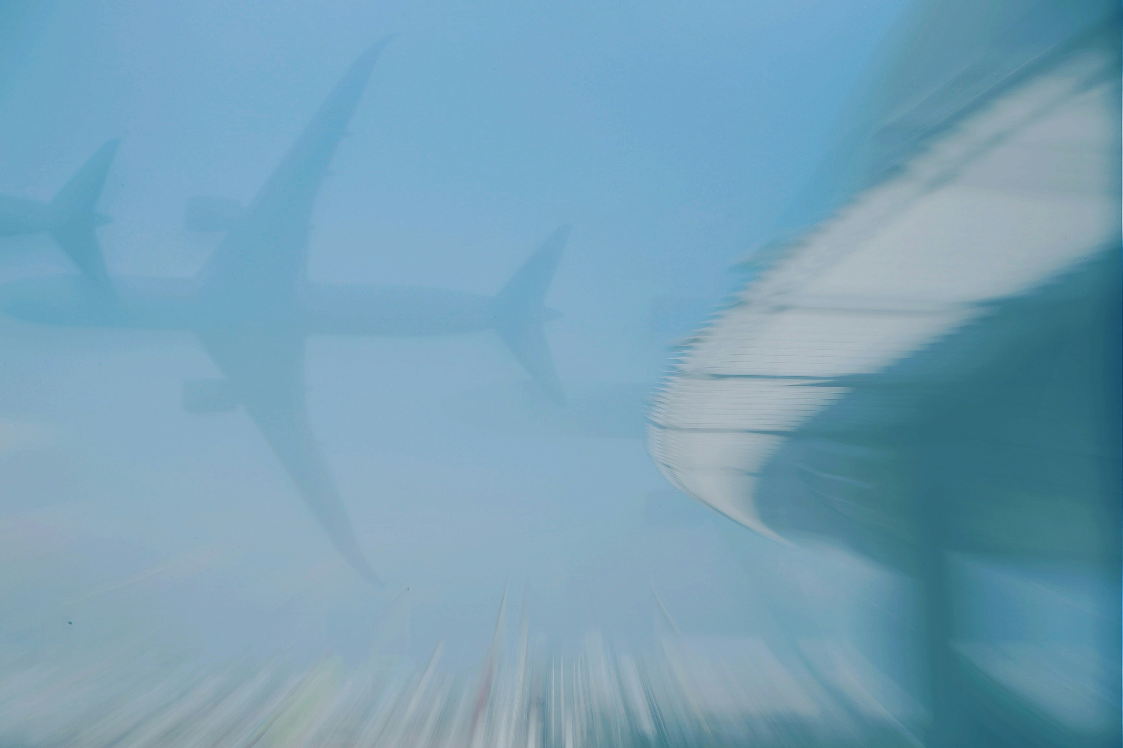 Blurred image of a shark and a boat's shadow underwater