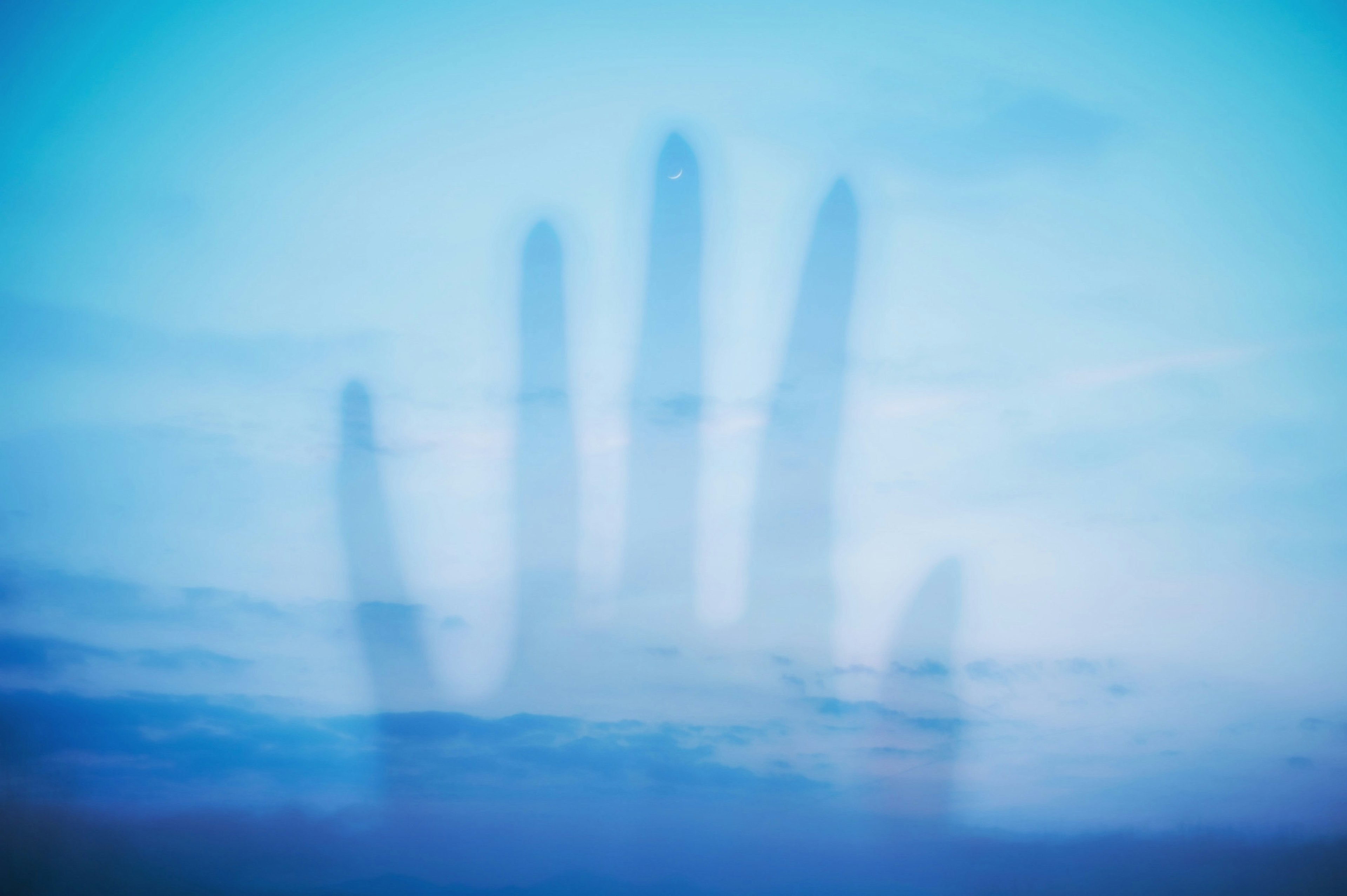 A shadow of a hand floating in a blue sky creates a surreal effect