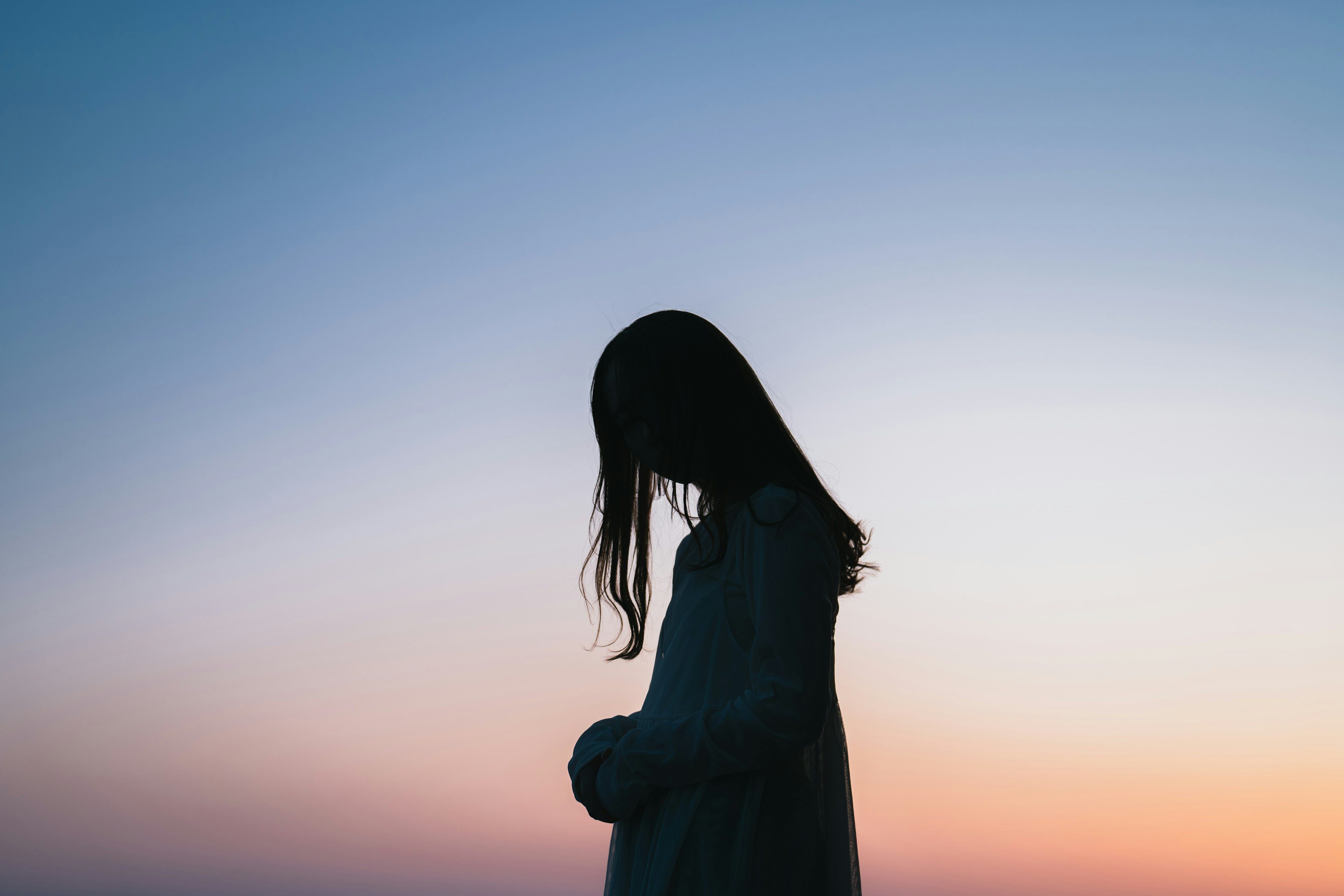 Silhouette einer Frau, die sich in der Dämmerung nach vorne lehnt