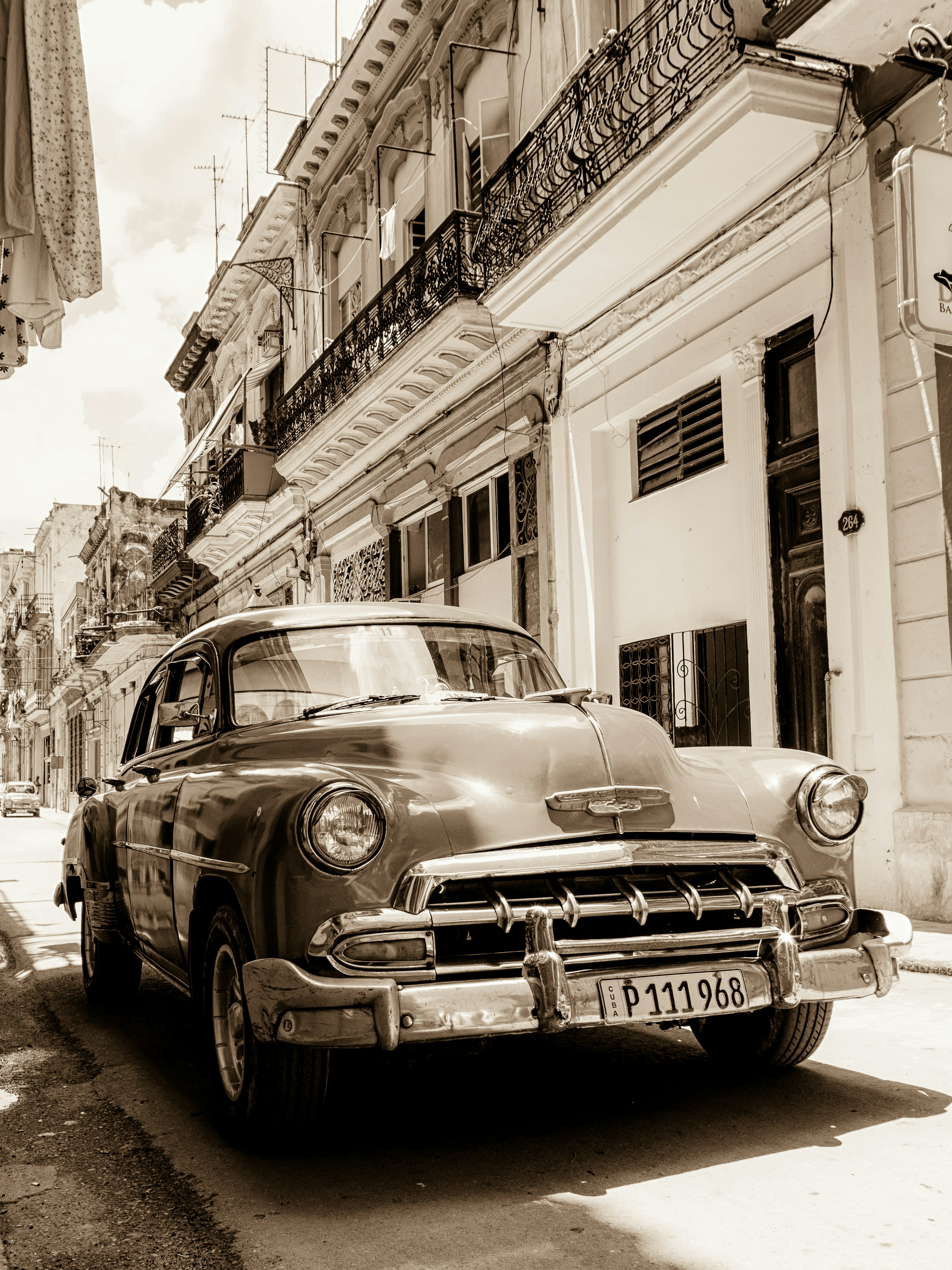 Vintage American car parked on a street with colorful buildings in the background