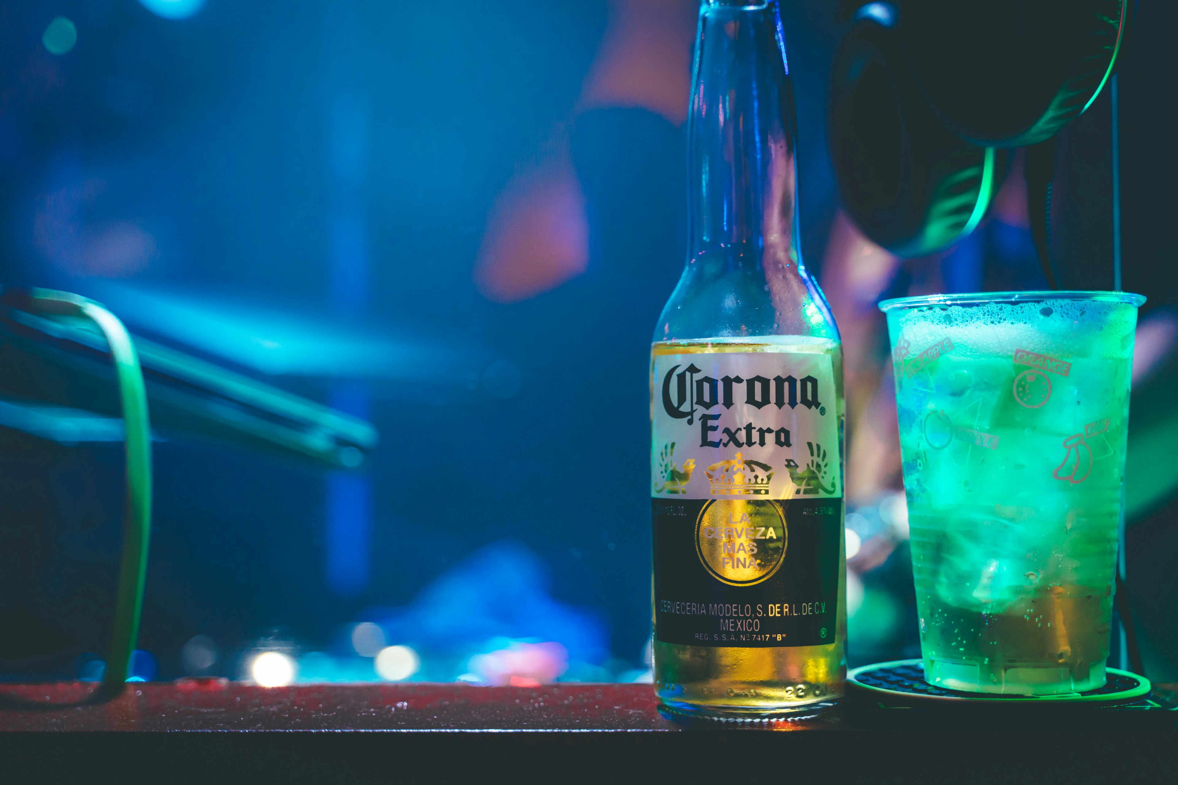 Corona beer bottle and cocktail glass in blue lighting