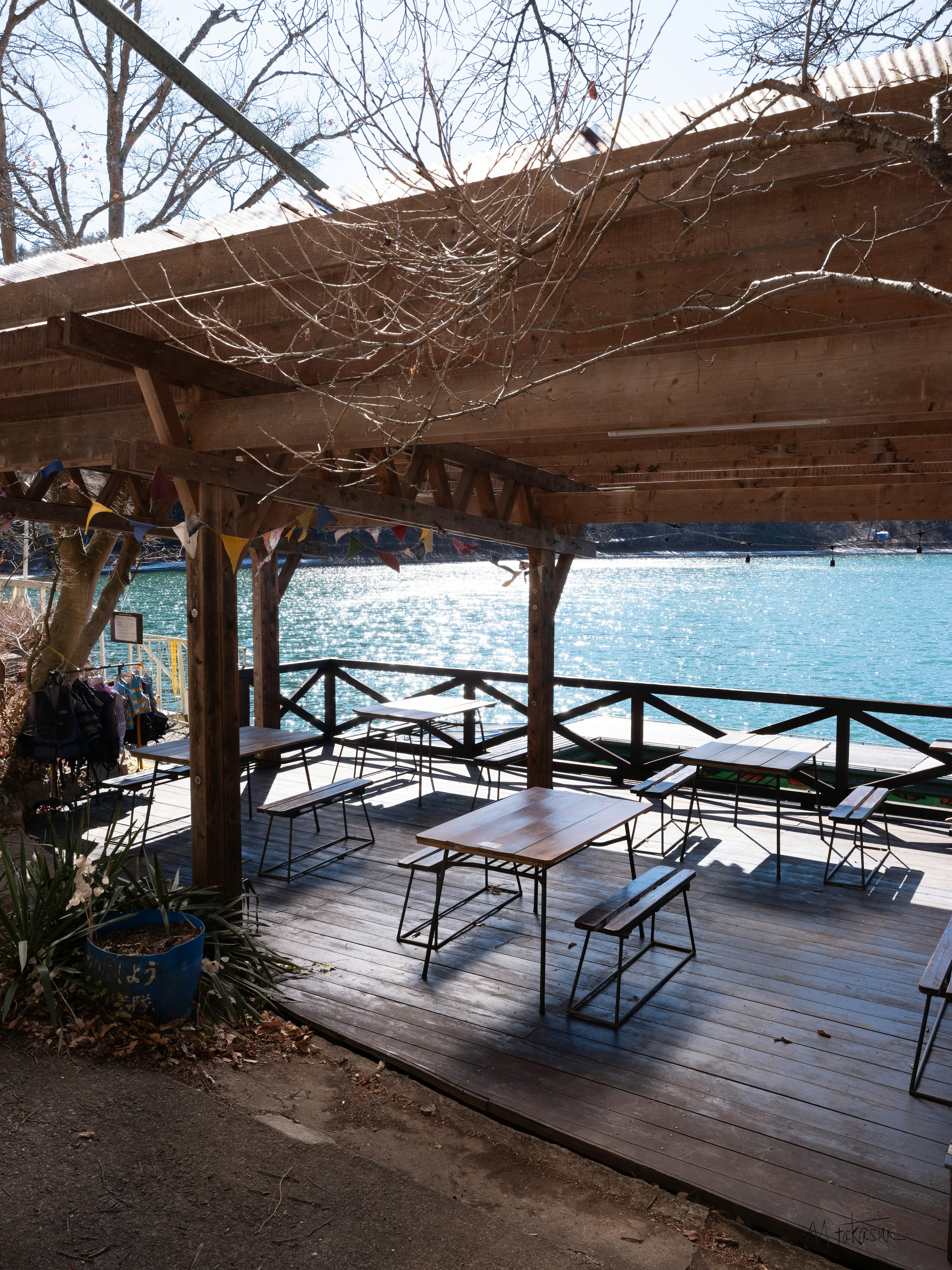 Terraza de madera junto al agua con mesas y sillas