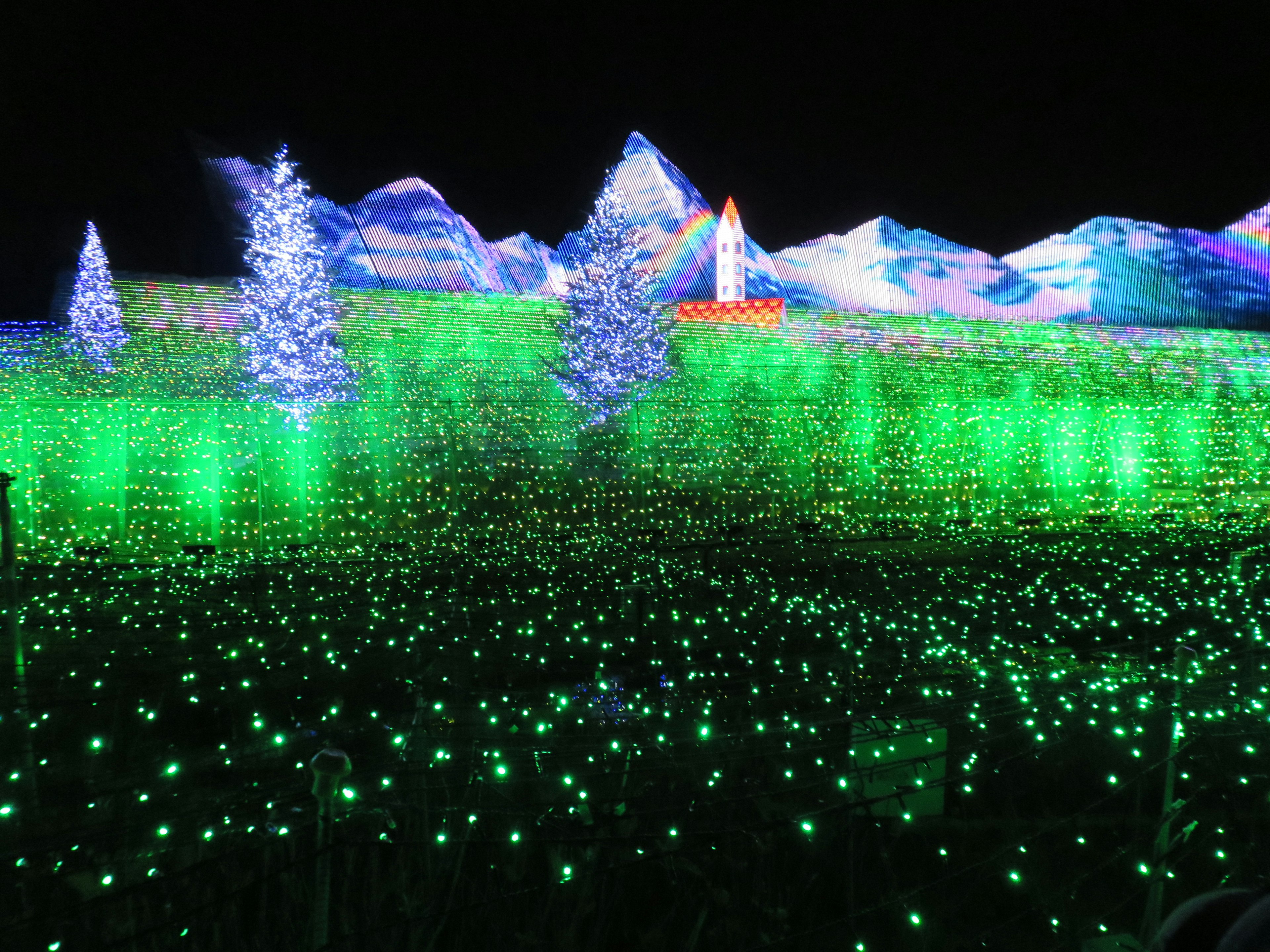 A magical landscape with glowing green lights, blue trees, and colorful mountains at night