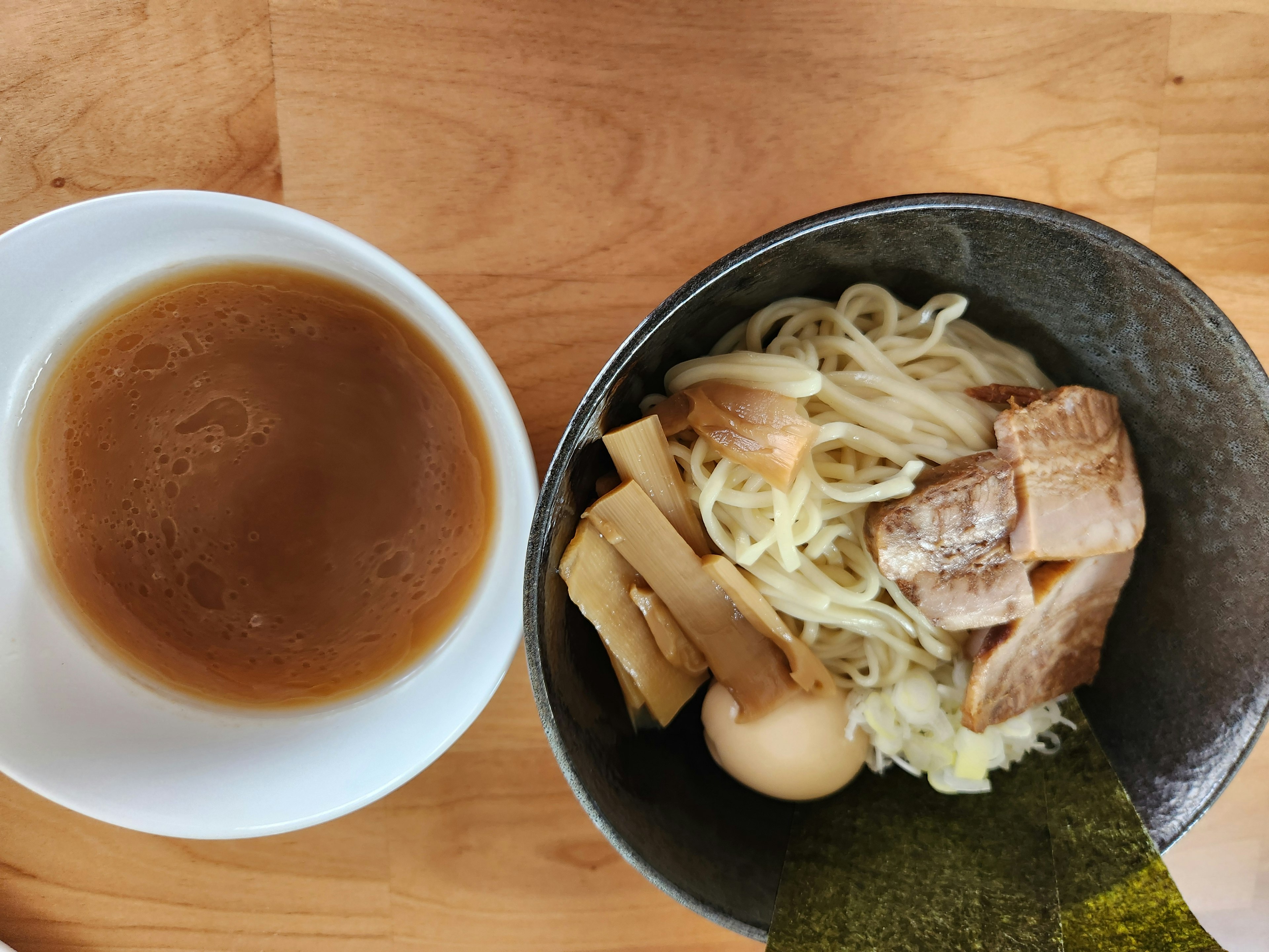 Un piatto di ramen con maiale, uovo e zuppa a lato