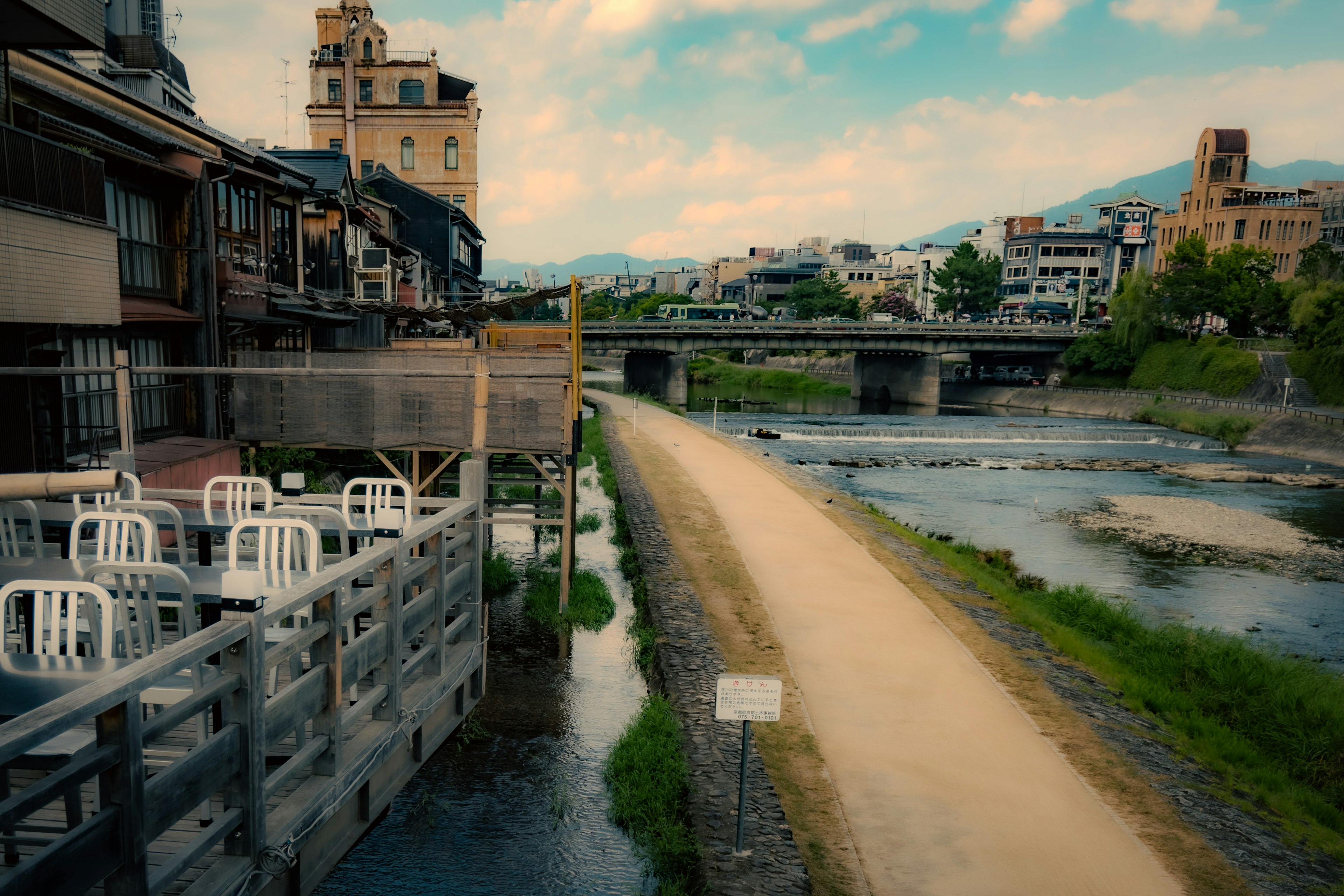 Riverside path with chairs arranged at a café overlooking the water