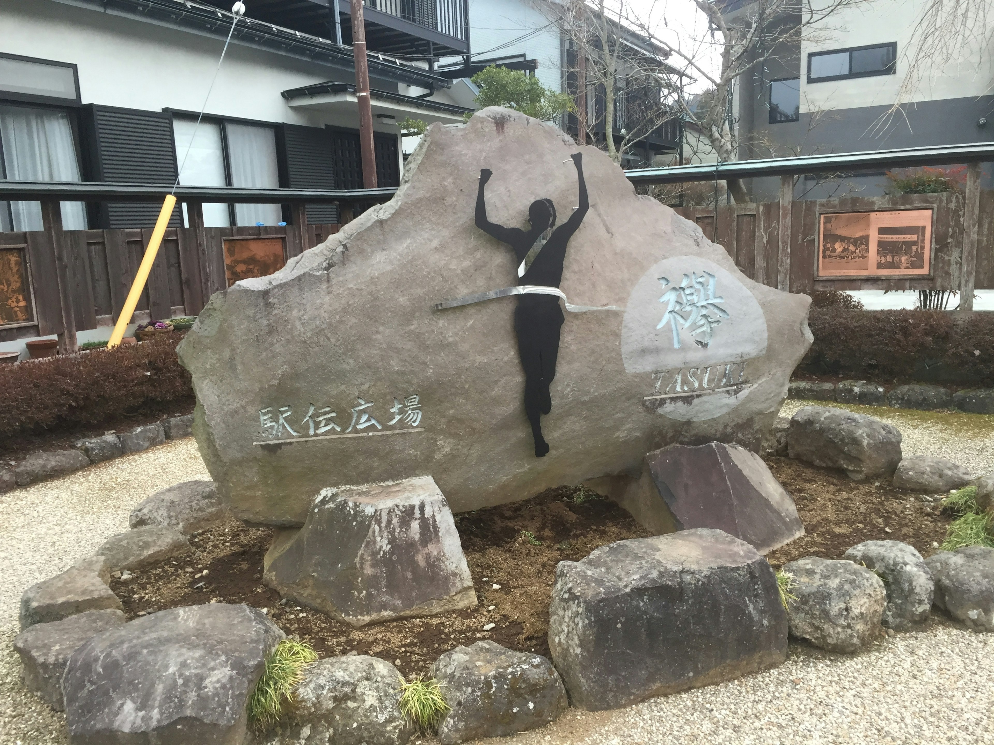 岩に登るシルエットの彫刻と周囲の石