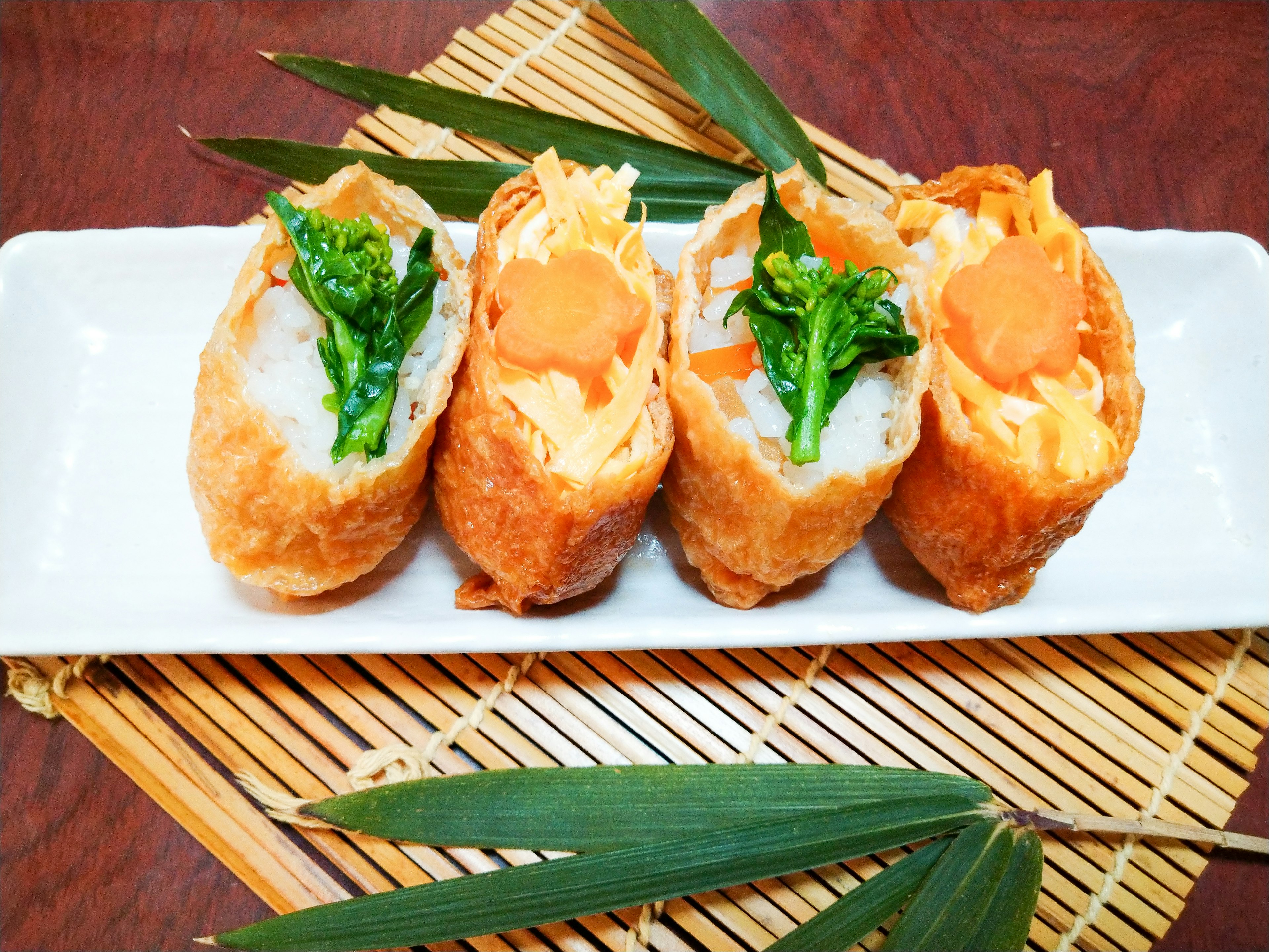 Fried spring rolls arranged on a white plate with bamboo leaves as decoration