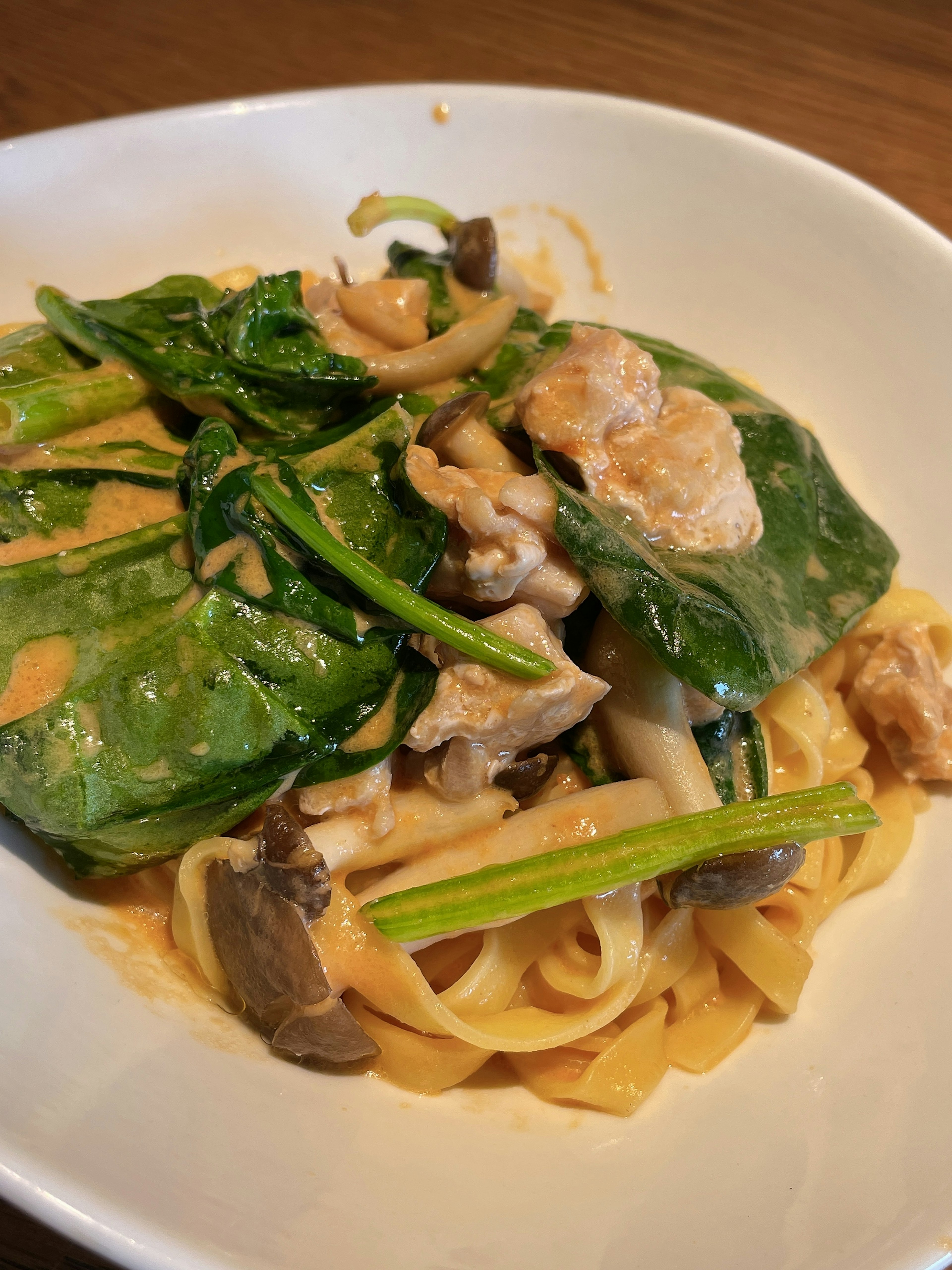 Pasta con salsa cremosa cubierta de espinacas y champiñones