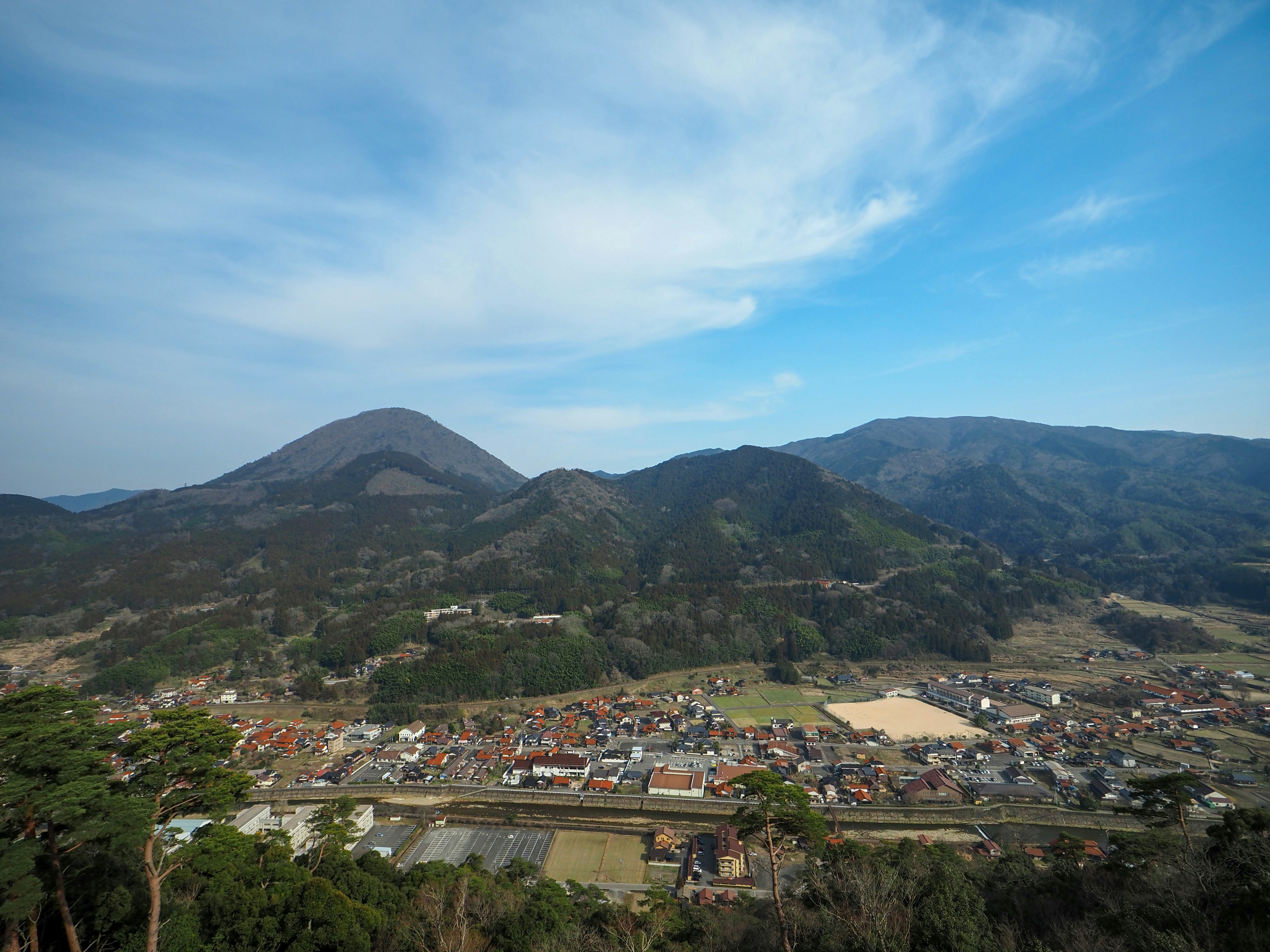 Landschaft mit Bergen und einem Dorf unter blauem Himmel