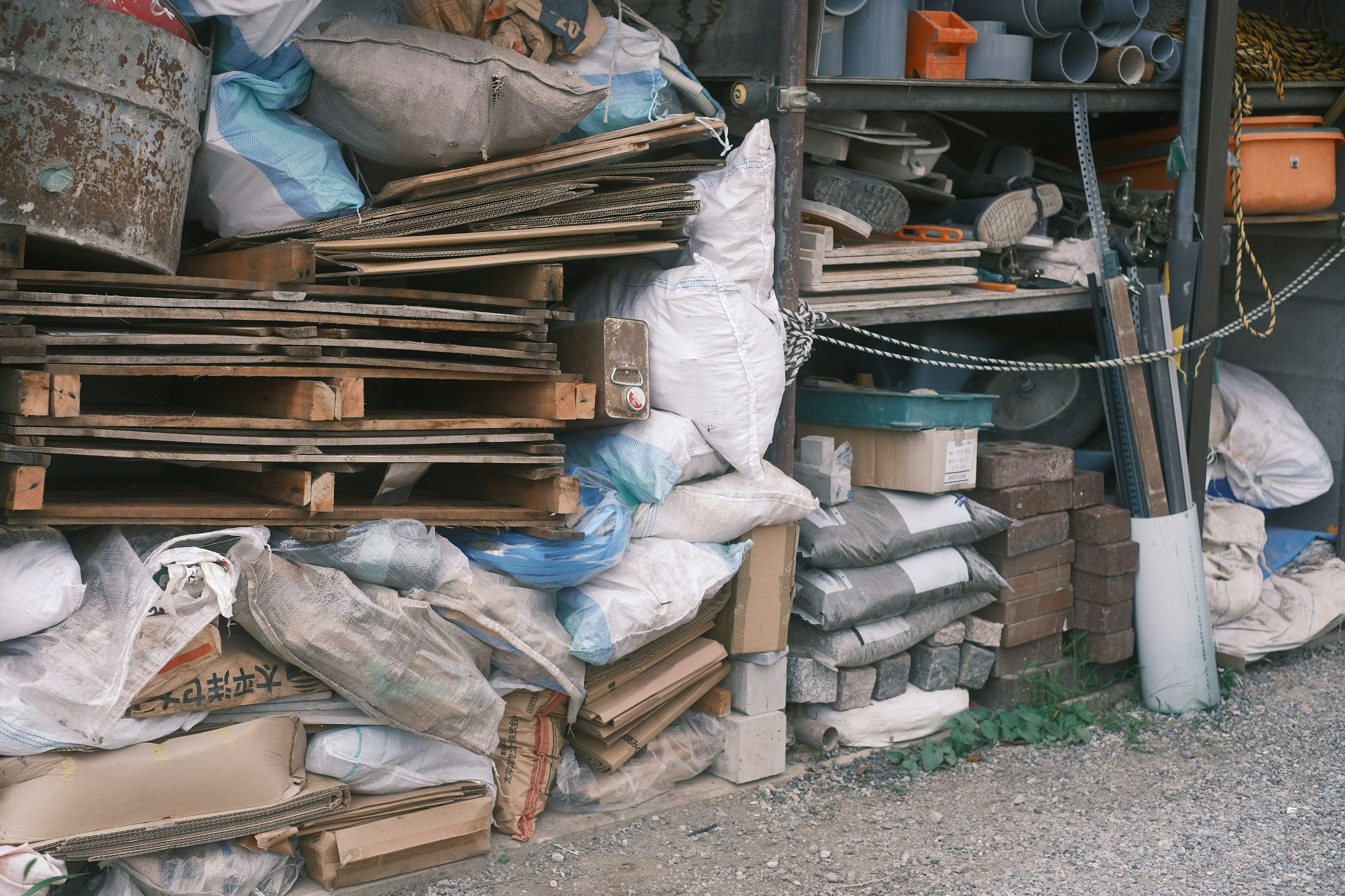 A corner of a storage area filled with stacked wooden pallets and bags of materials