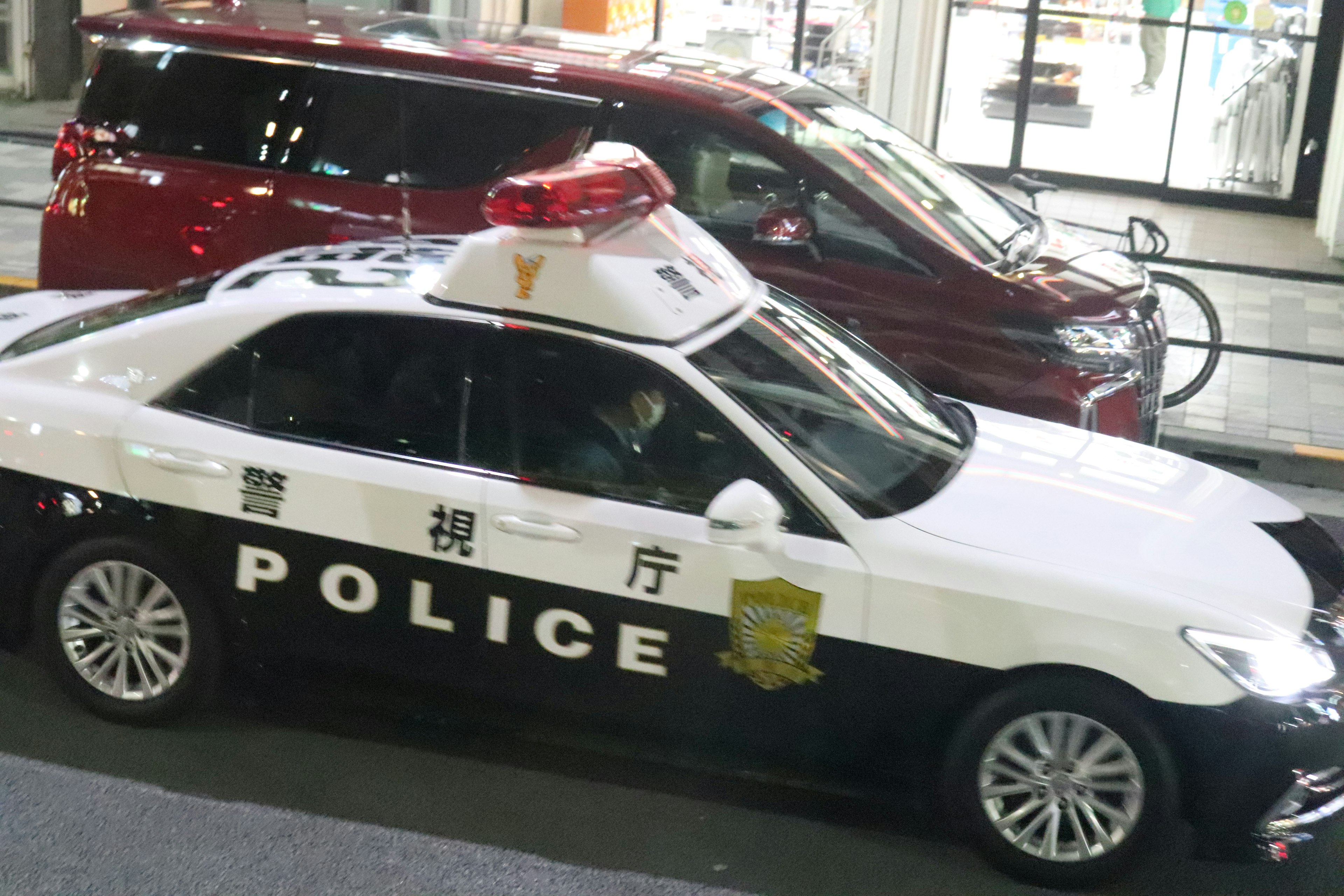 A black and white police car parked on a city street at night