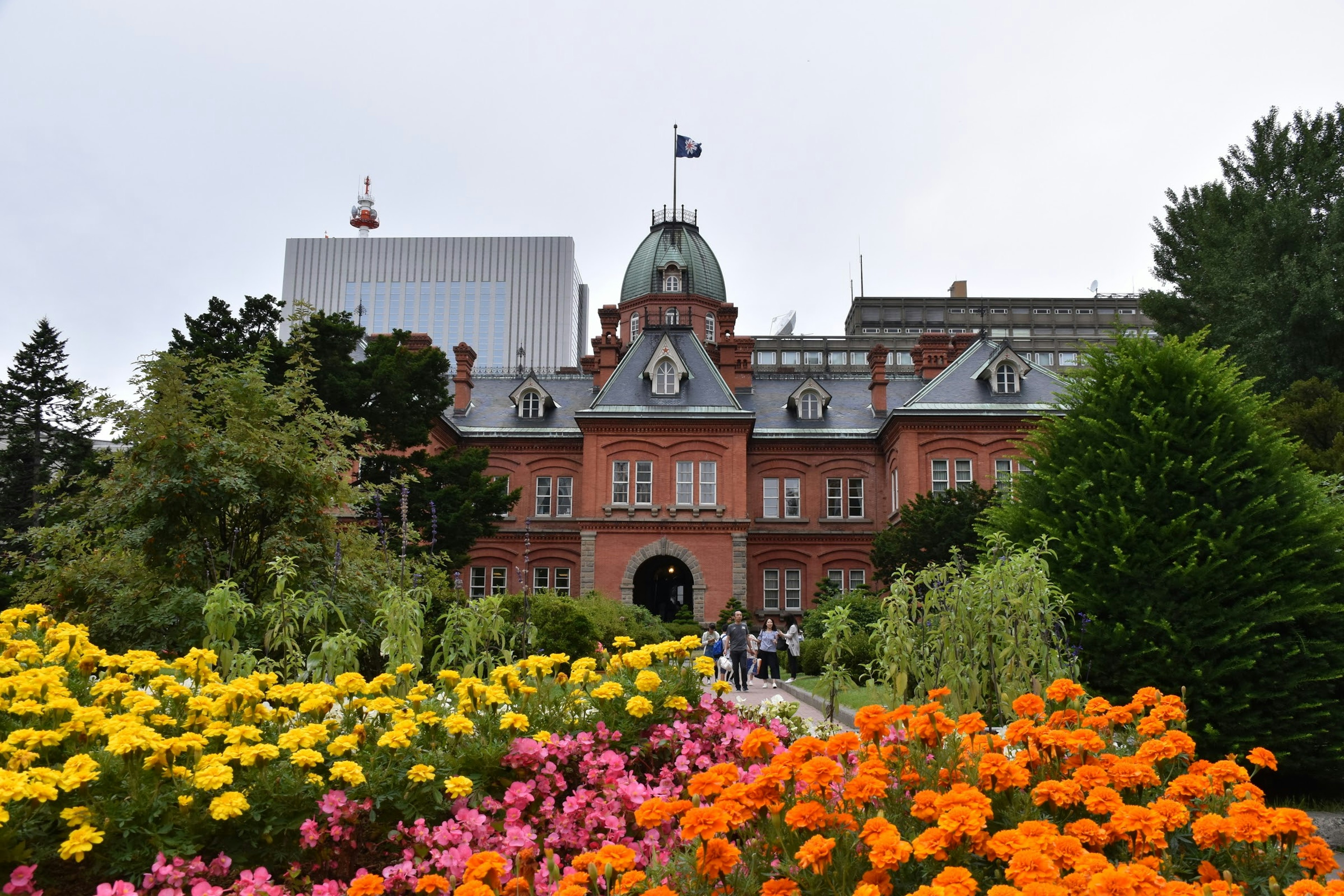 赤レンガの建物と色とりどりの花が咲く庭園