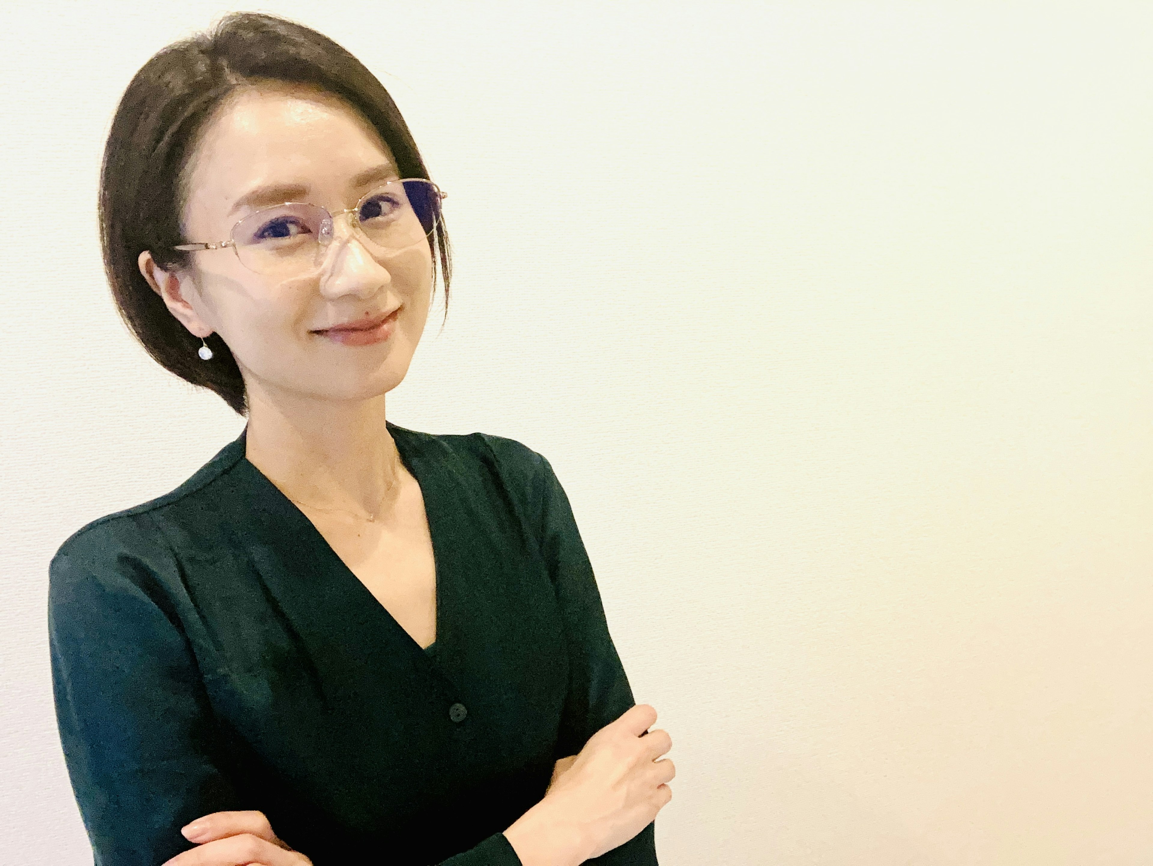 A woman in a black outfit smiling with arms crossed