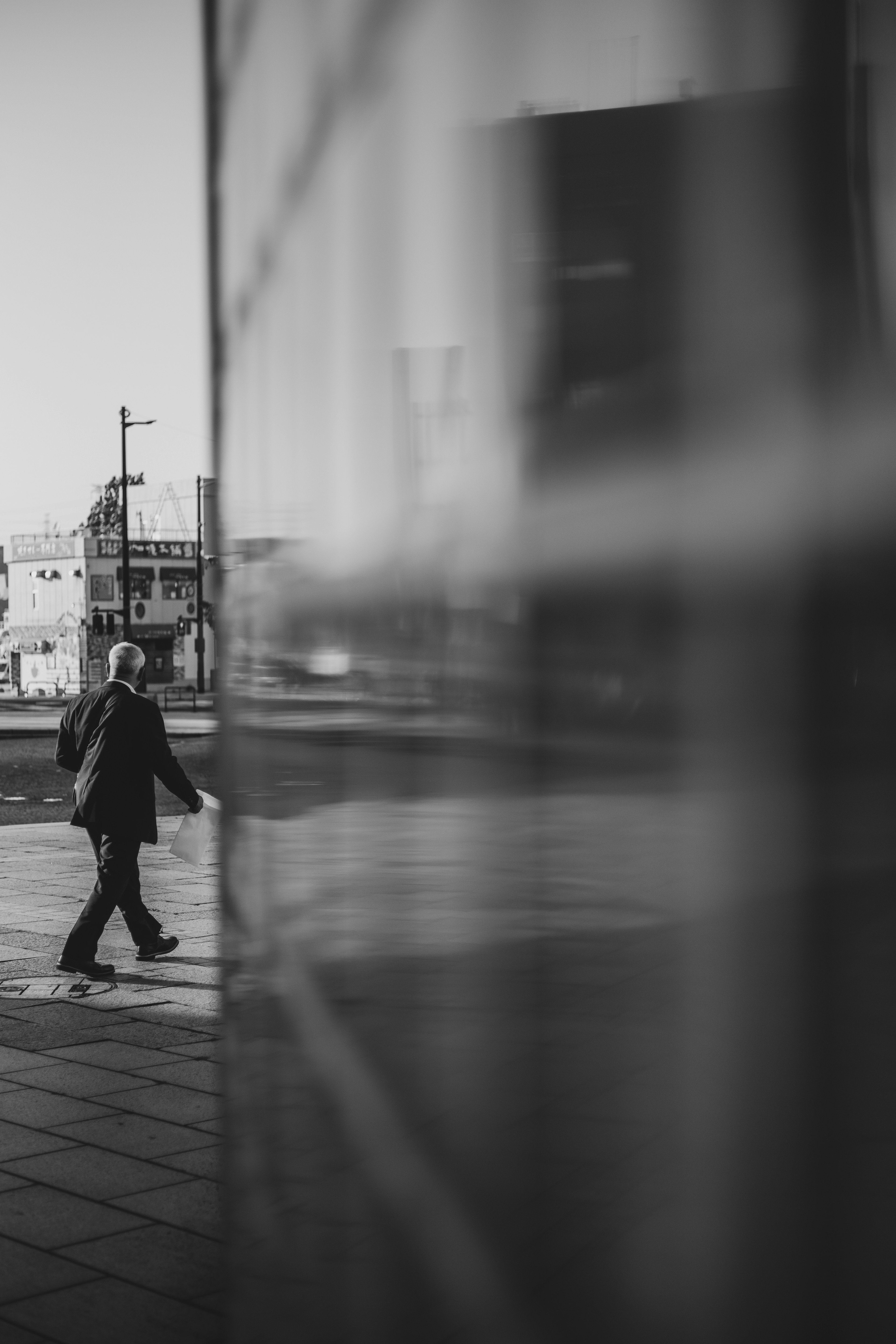 Silhouette di un uomo che cammina in città riflessa su una superficie di vetro