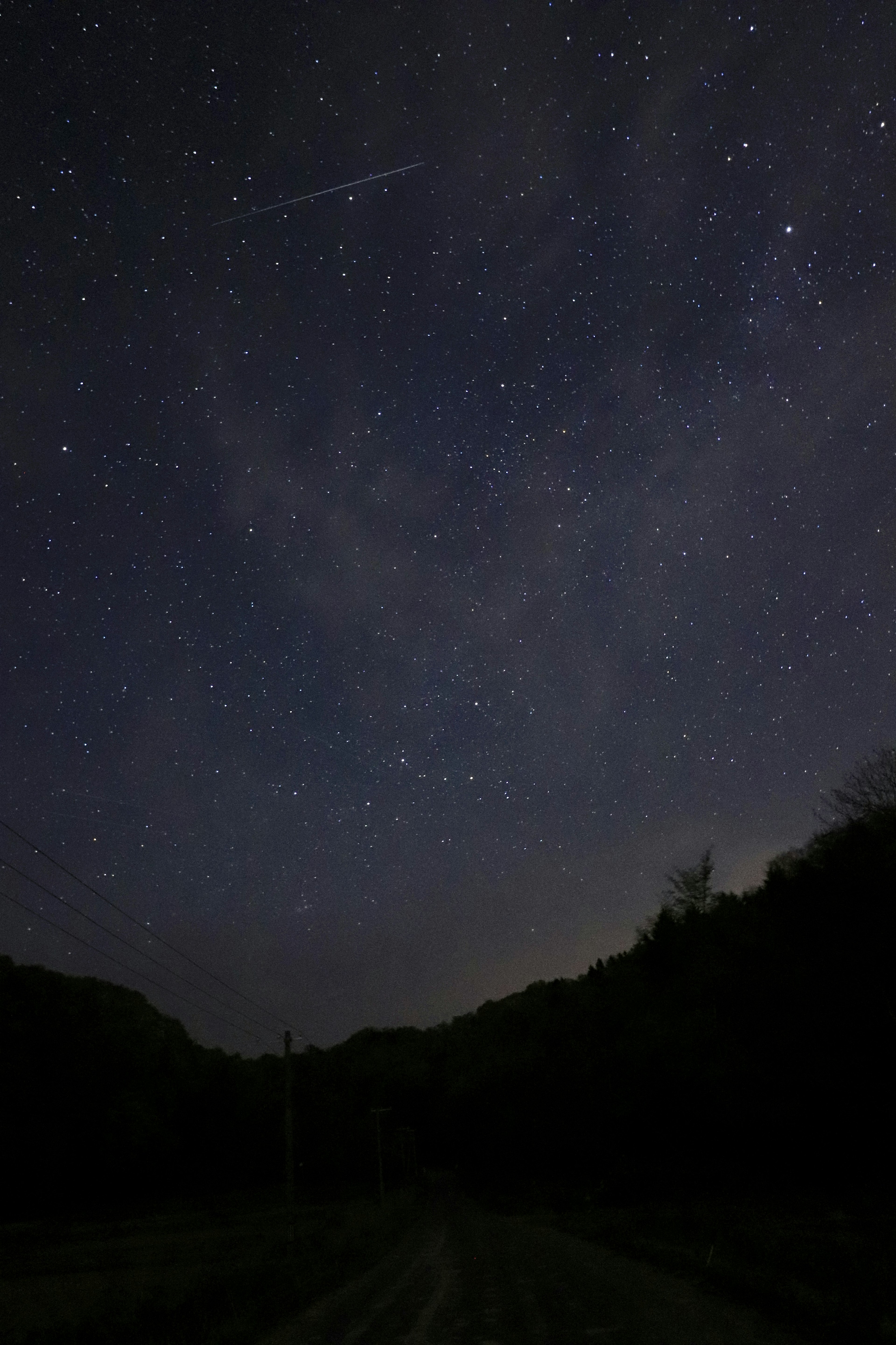 Un ciel nocturne clair rempli d'innombrables étoiles et une étoile filante visible