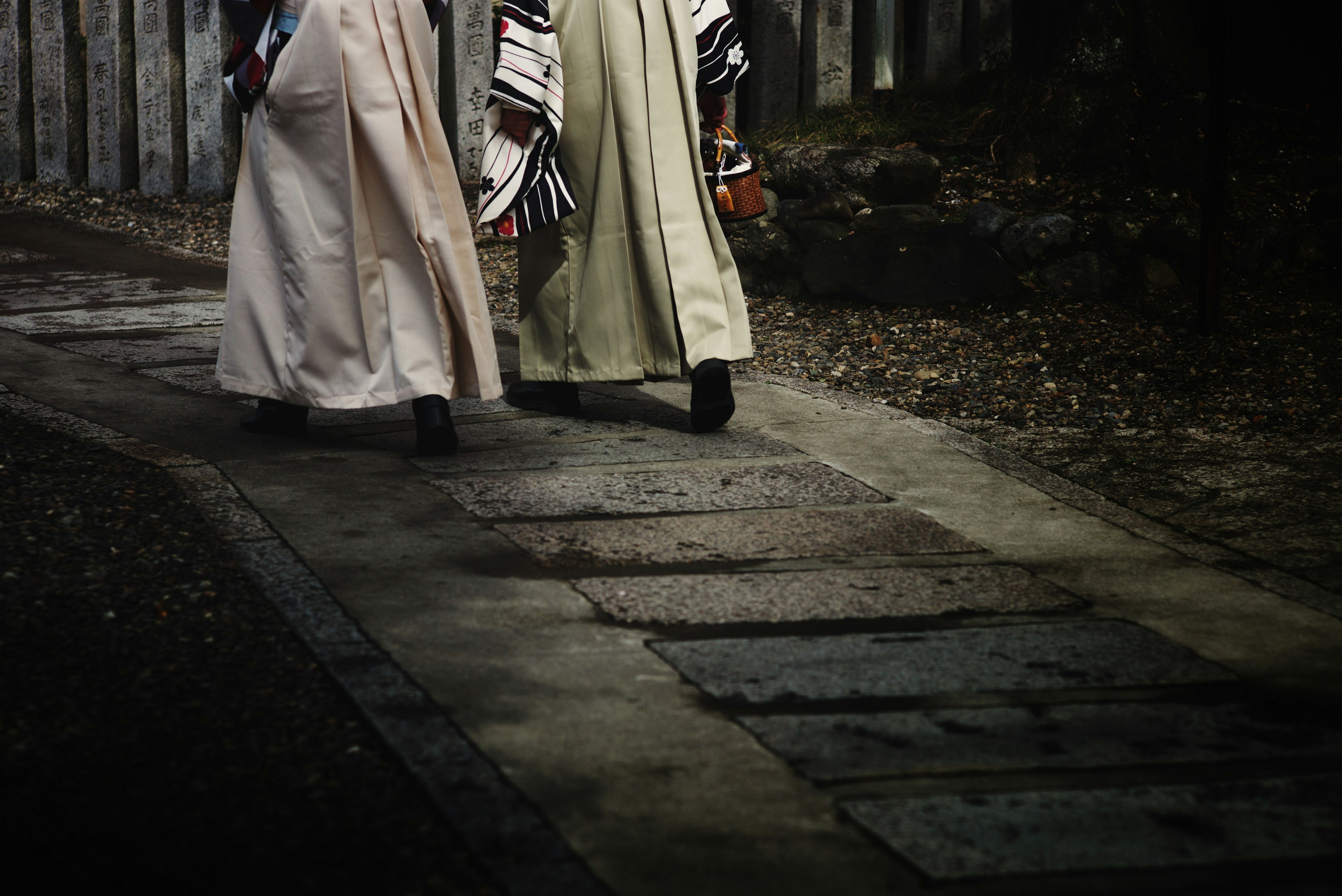Two women walking in traditional clothing on a stone pathway
