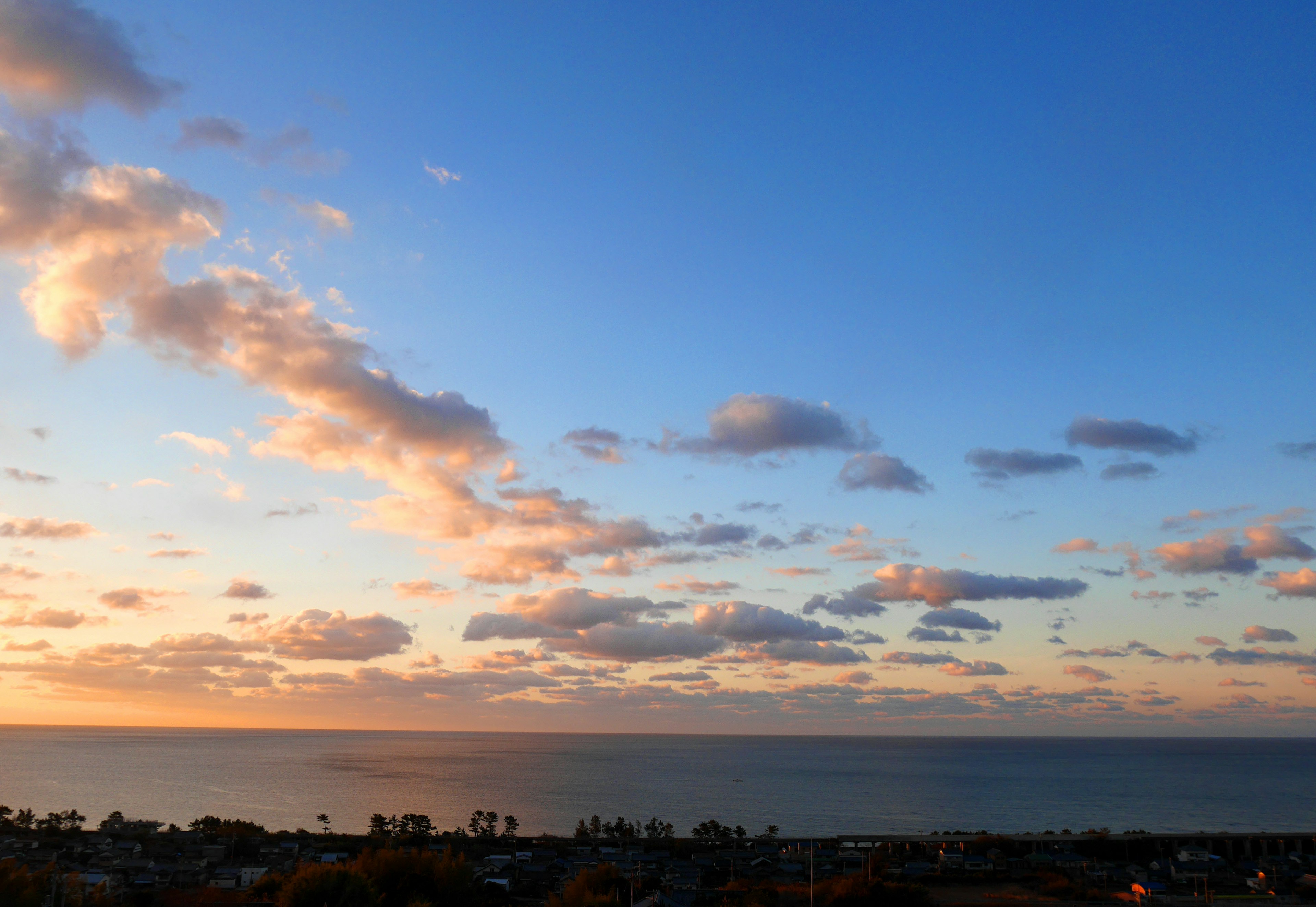 Une vue panoramique d'un ciel bleu avec des nuages orange sur l'océan