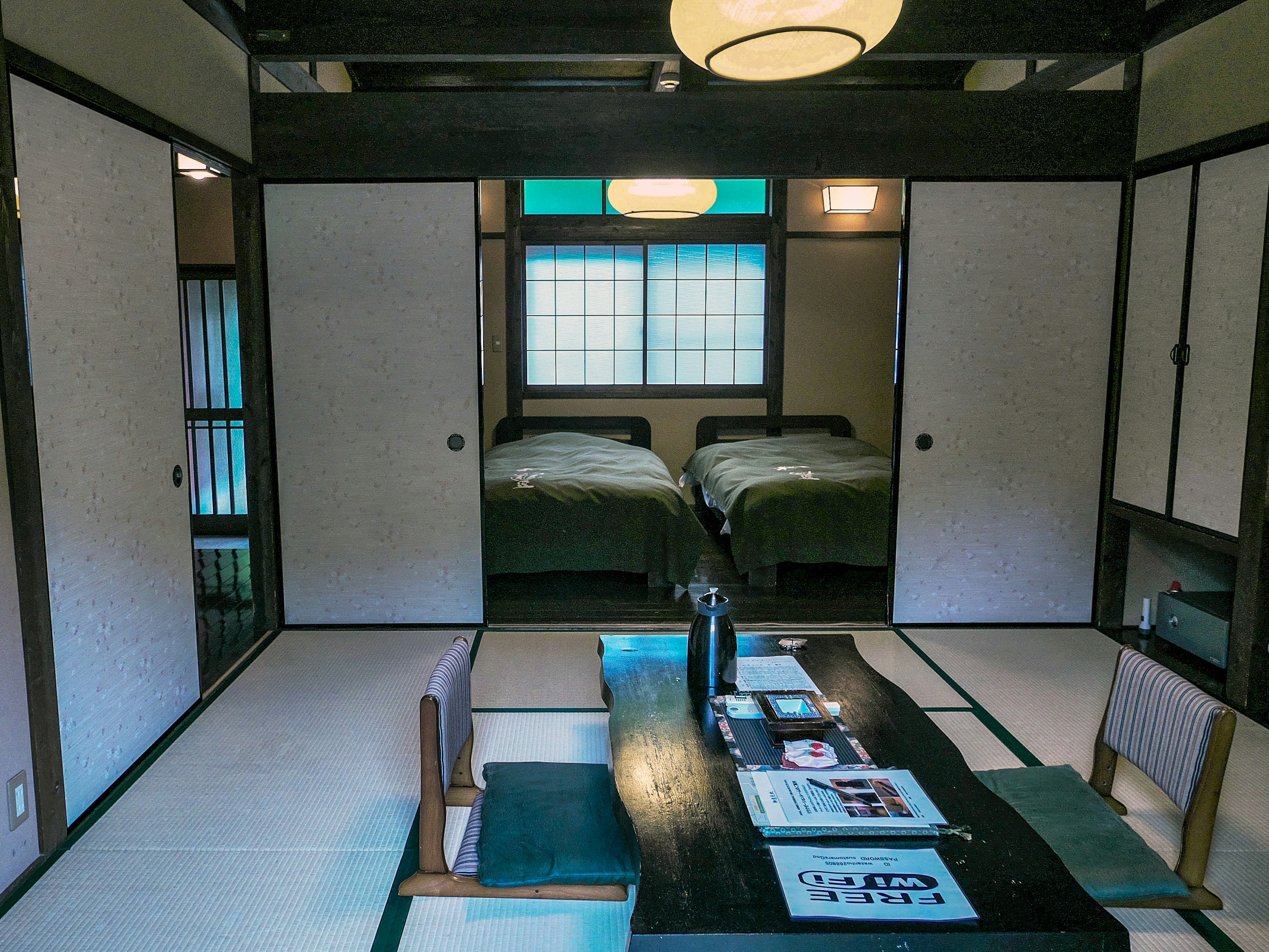 Interior de una habitación japonesa tradicional con una mesa baja y dos dormitorios visibles