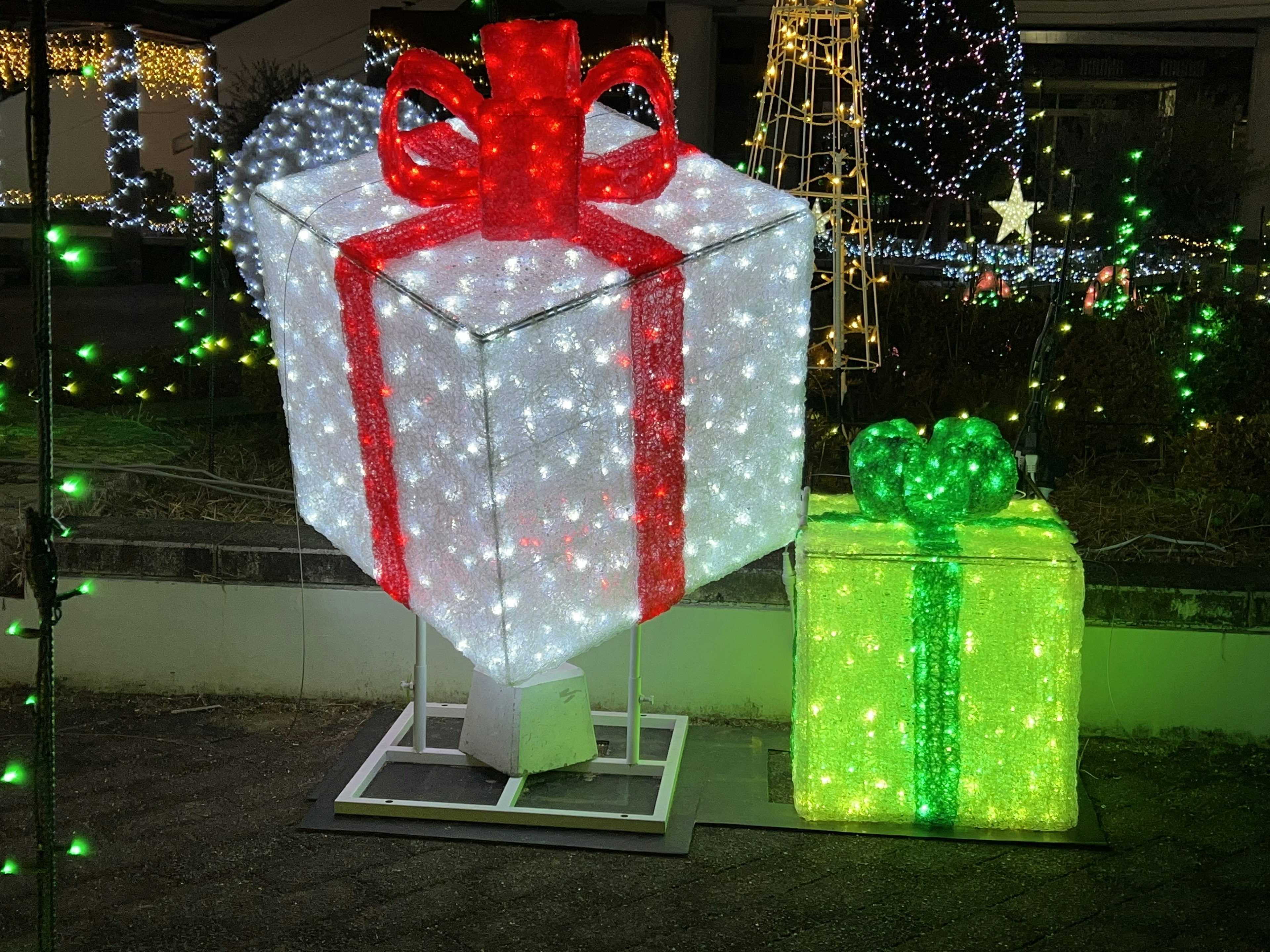 Grande boîte cadeau illuminée avec un ruban rouge et une petite boîte cadeau verte à côté